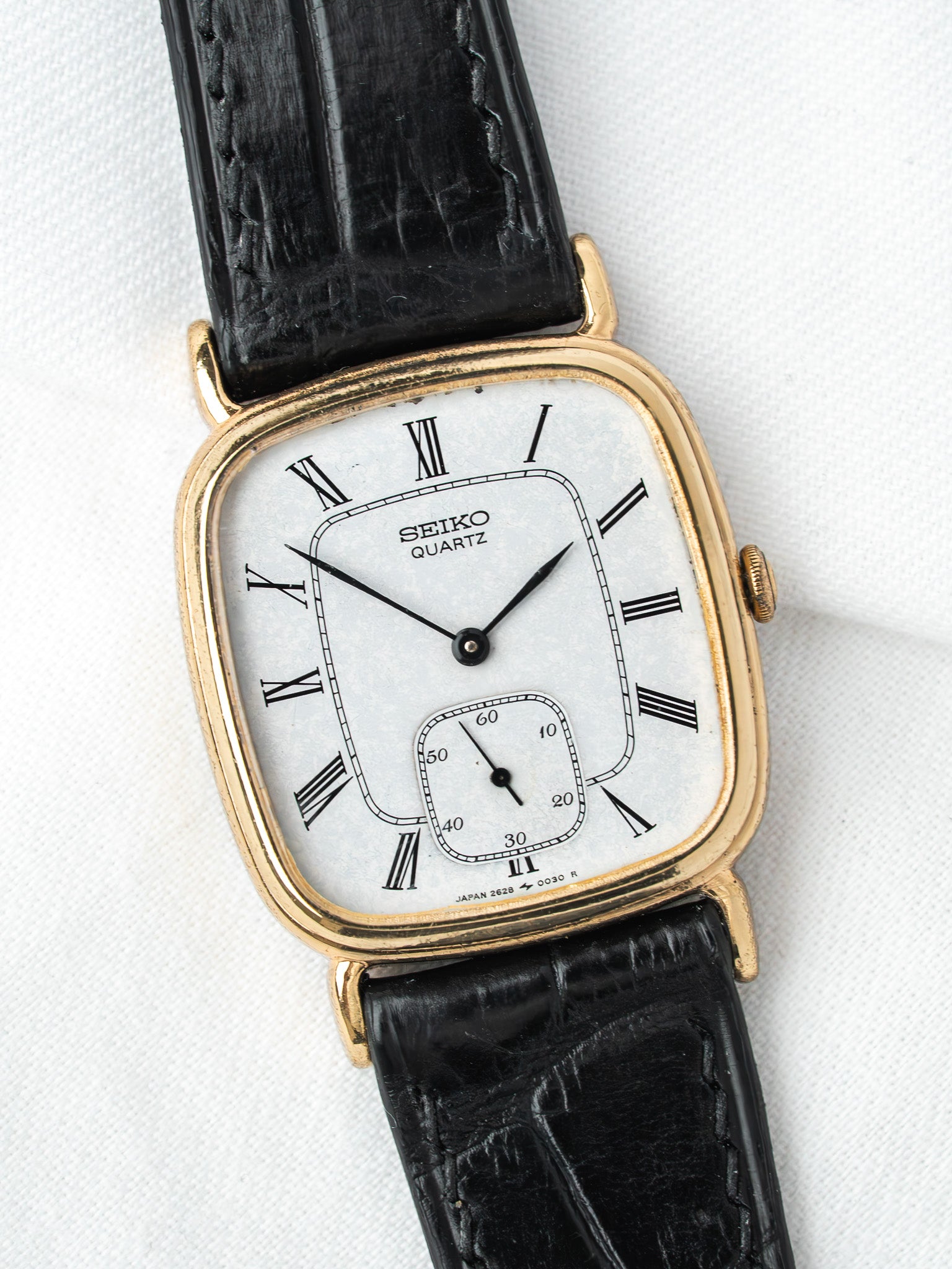 Seiko Quartz vintage watch with gold case, white dial, Roman numerals, black leather strap