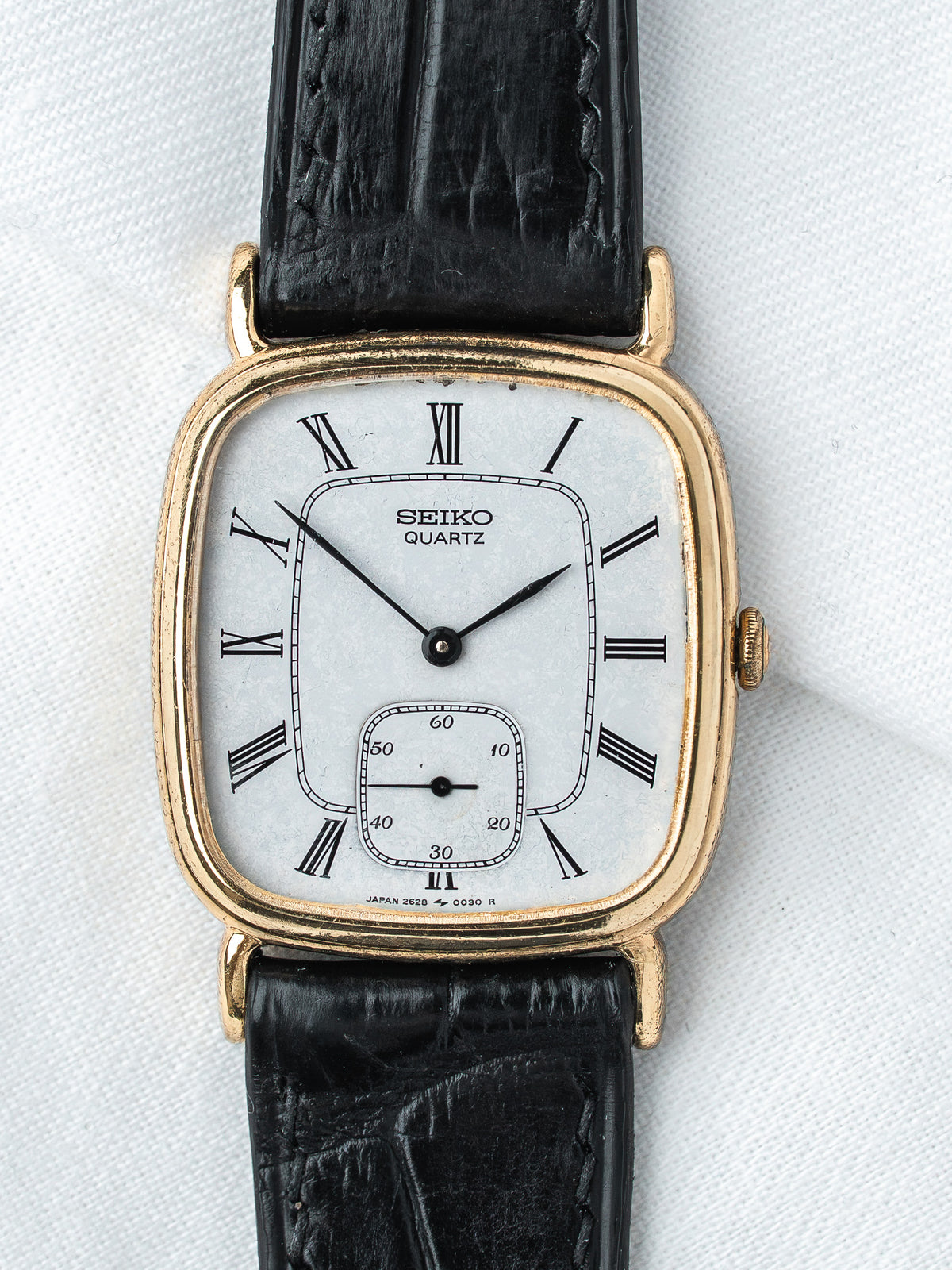 Seiko Quartz vintage watch with gold case, white dial, Roman numerals, black leather strap