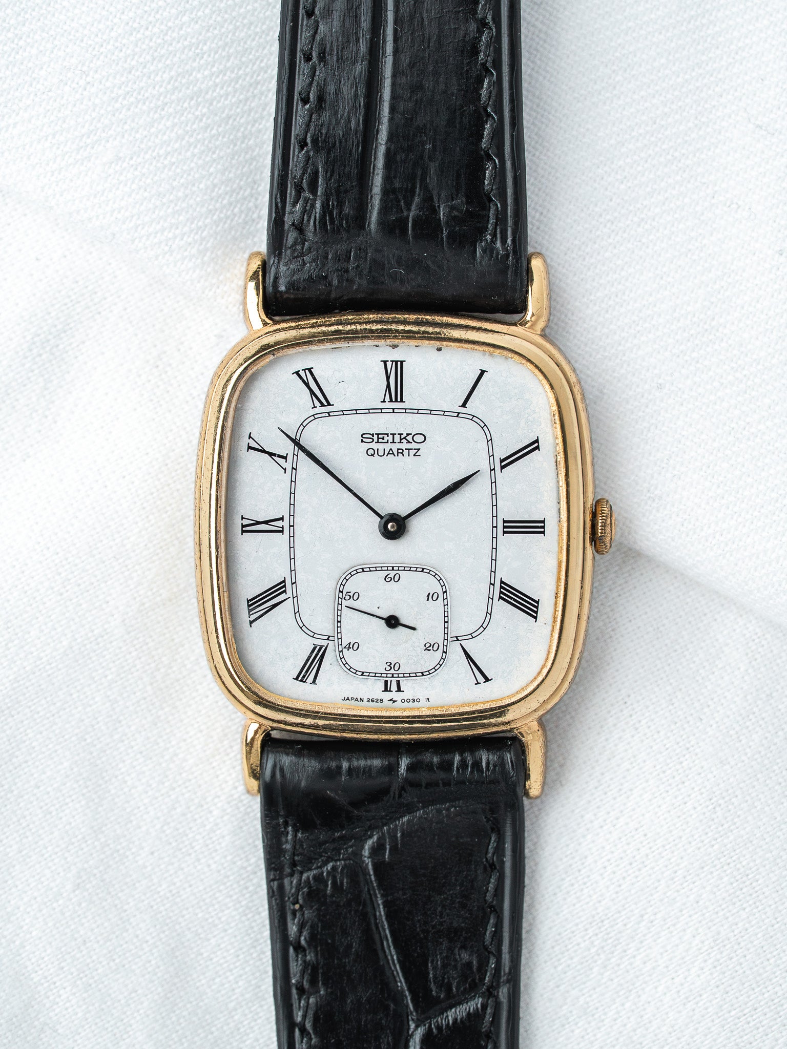 Seiko Quartz vintage watch with gold case, white dial, Roman numerals, black leather strap