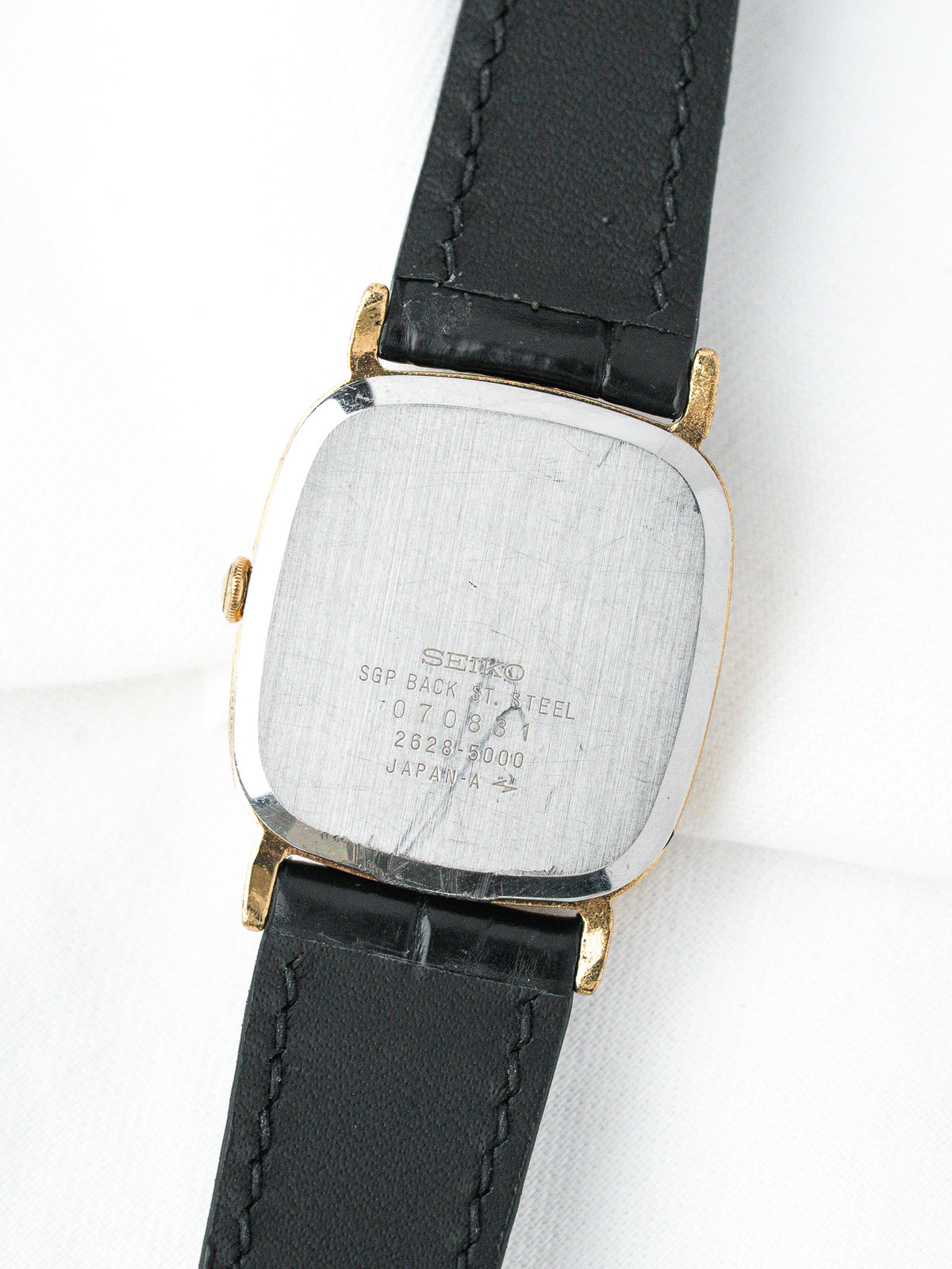 Seiko vintage watch with gold-tone case, black leather strap, steel back engraved
