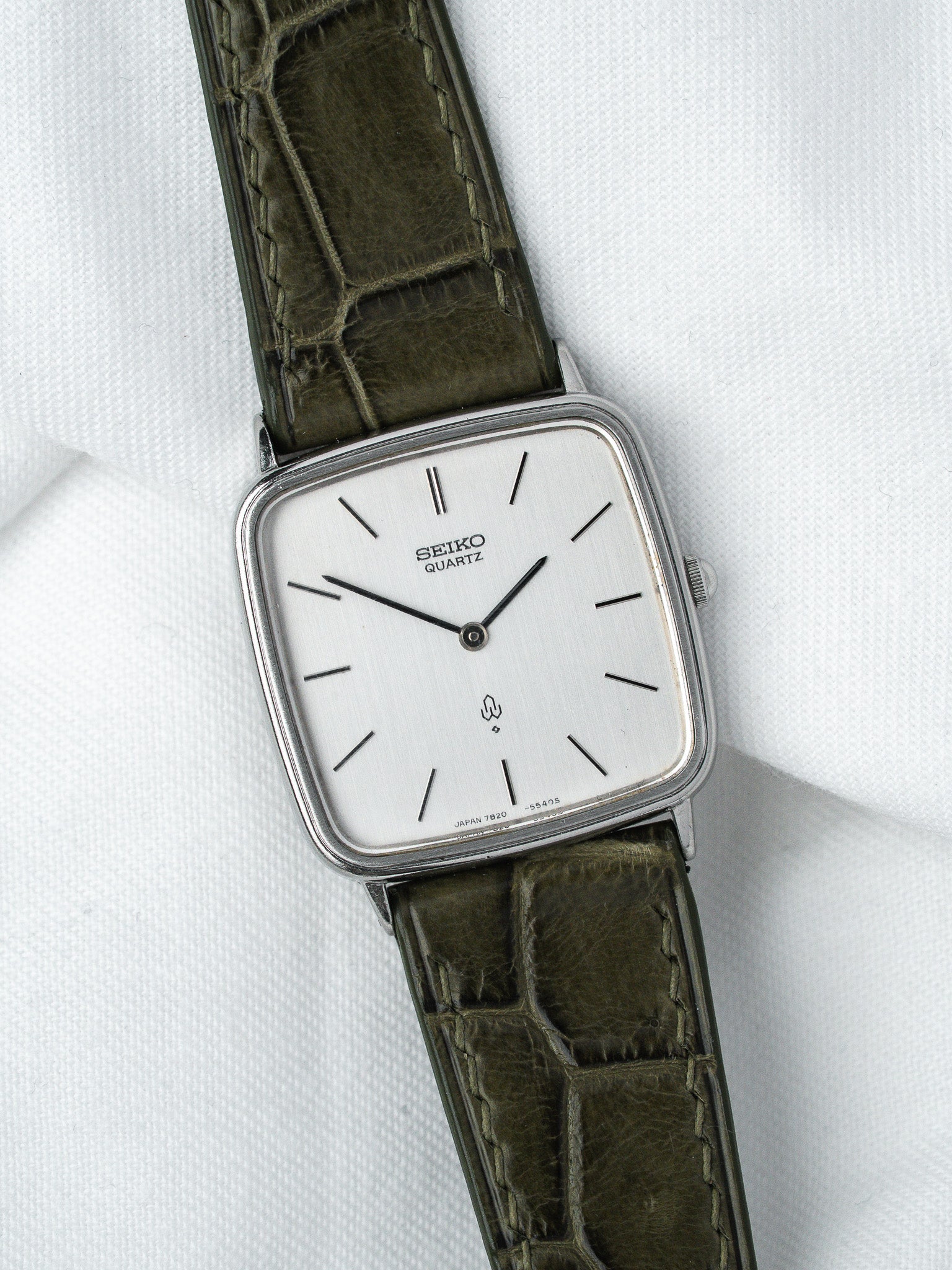 Seiko Quartz vintage watch with silver dial, olive crocodile strap, square case on white fabric