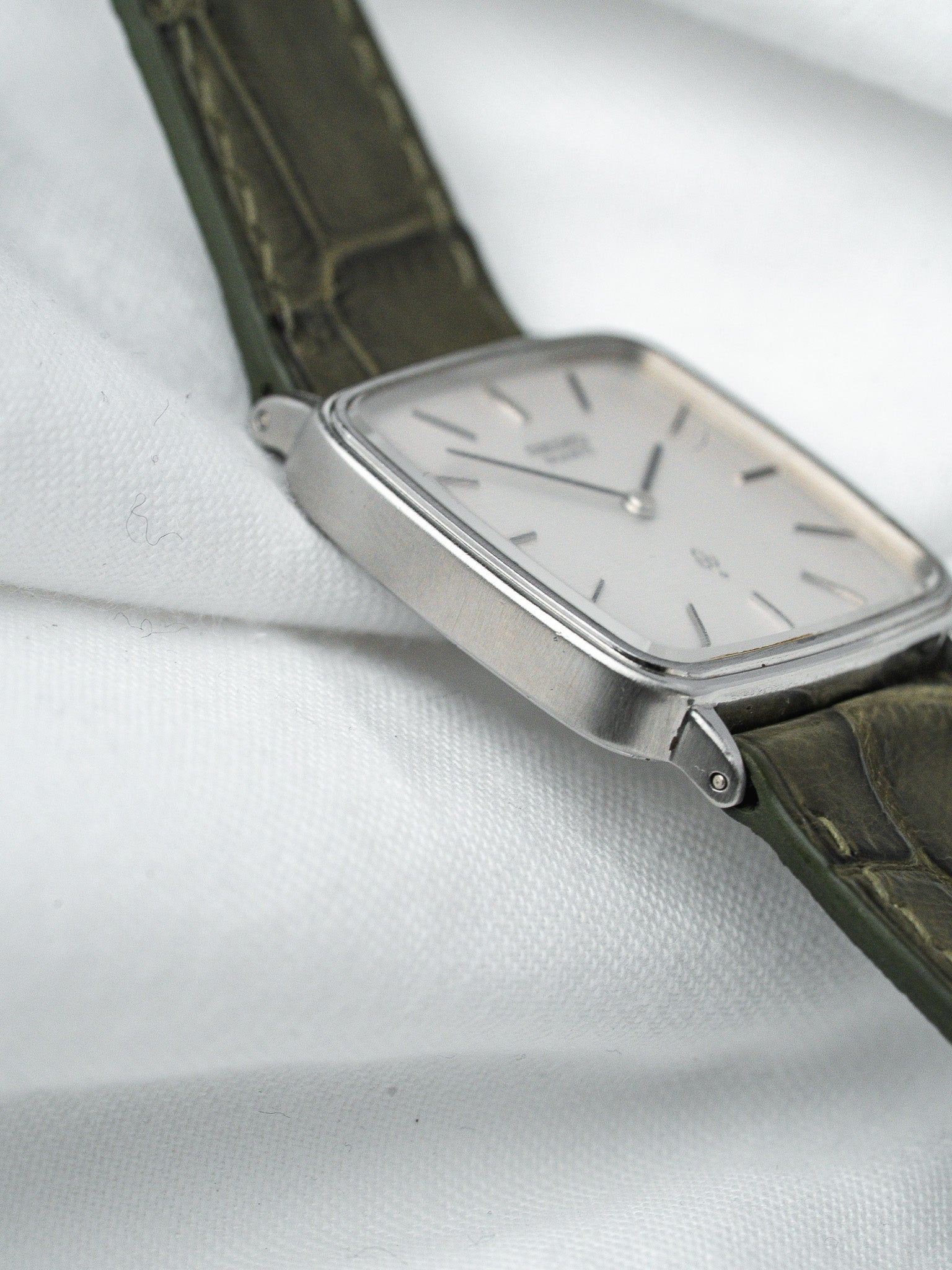 Vintage Universal Genève rectangular watch with silver dial and olive green leather strap