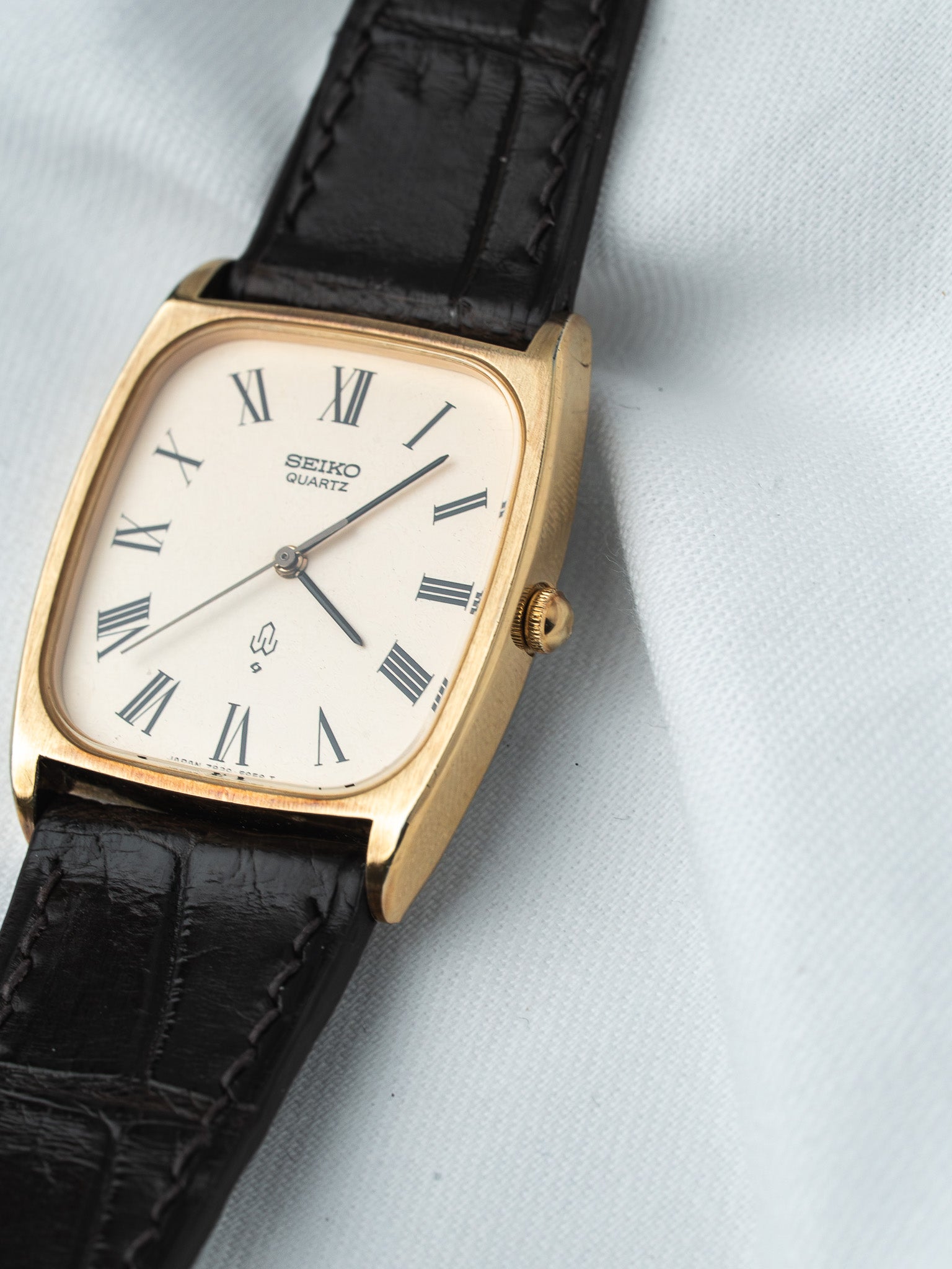 Seiko Quartz vintage watch with gold case, white dial Roman numerals, black leather strap