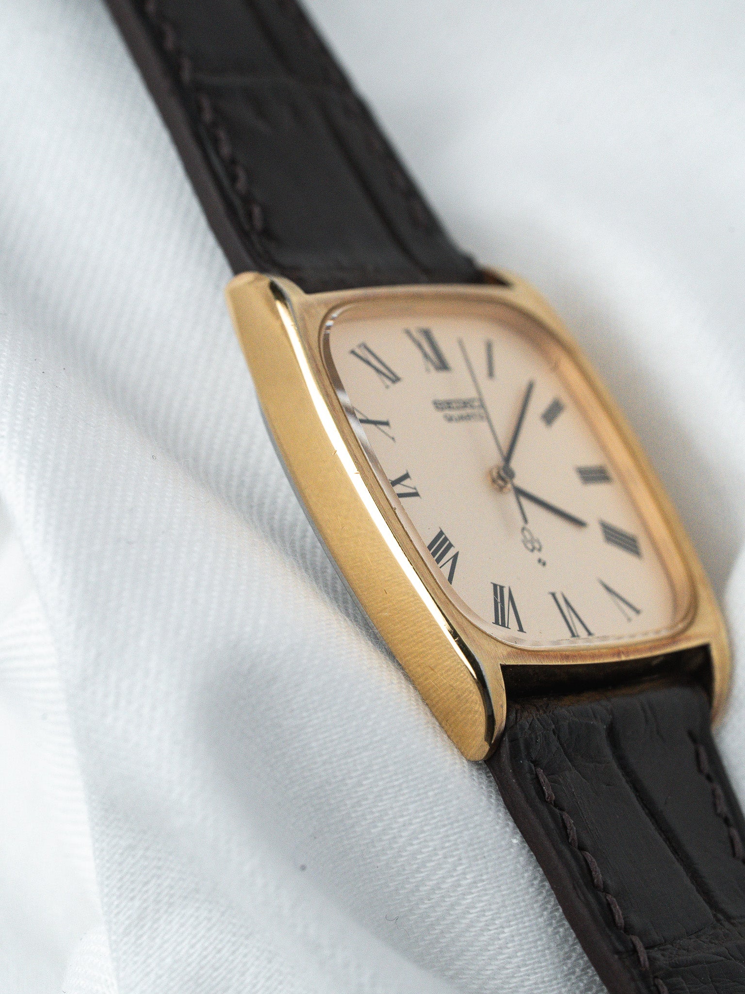 Montre Universal Genève vintage, boîtier doré, cadran crème chiffres romains, bracelet cuir noir