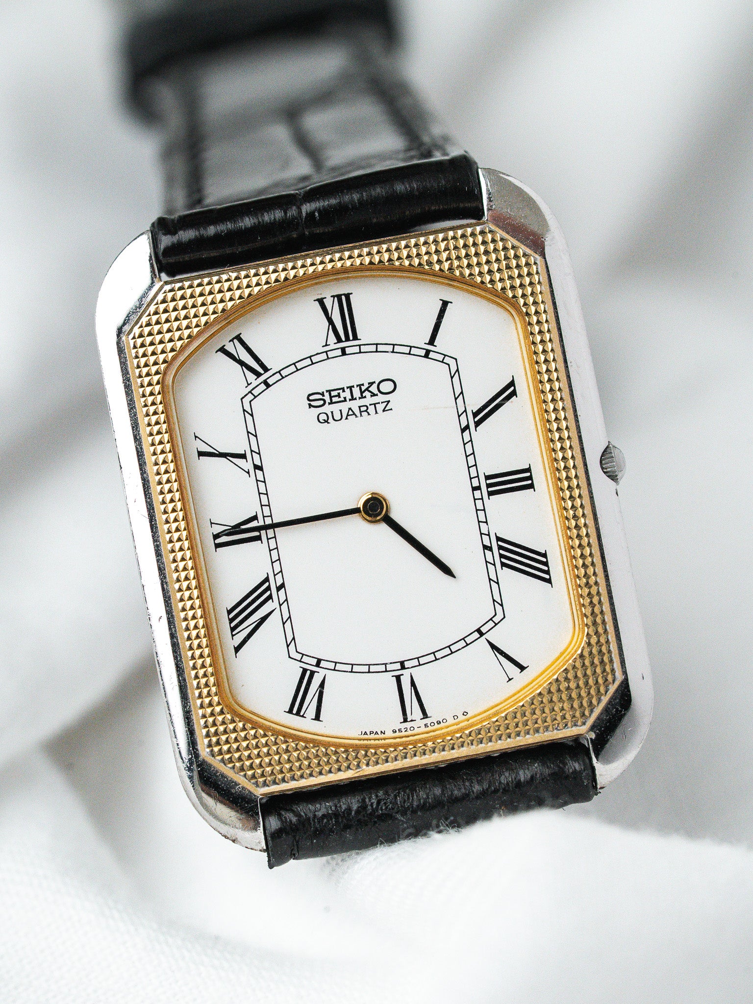 Seiko Quartz vintage watch with gold bezel, white dial, Roman numerals, black leather strap