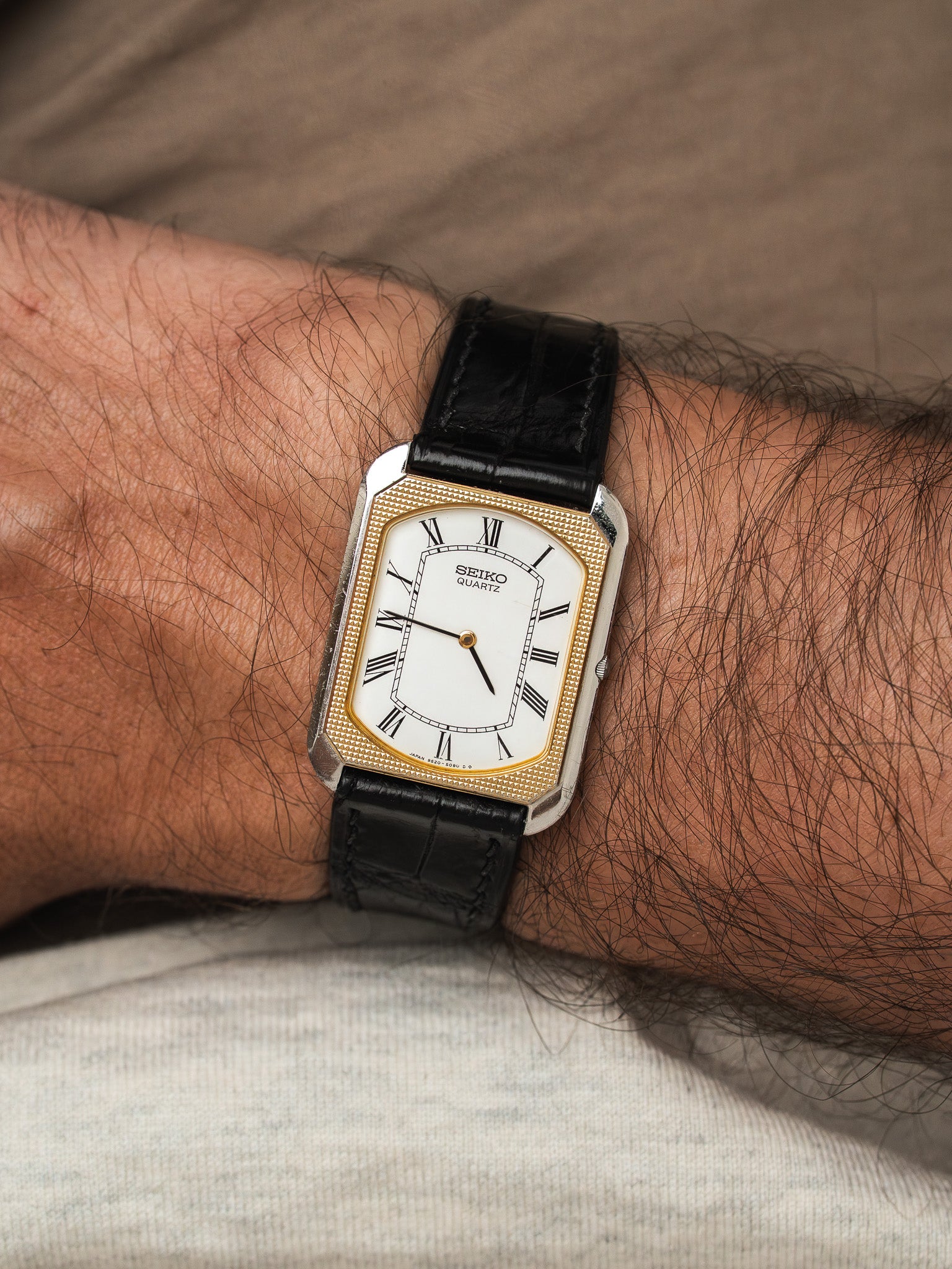 Seiko Quartz vintage watch with white dial, gold bezel, black leather strap on wrist