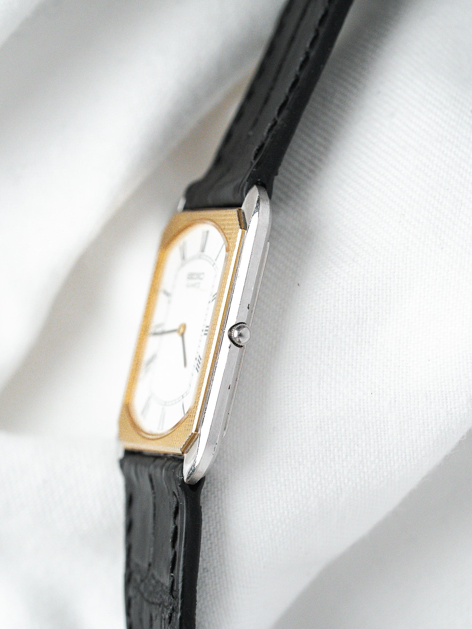 Seiko vintage watch with gold-tone case, white dial, and black leather strap
