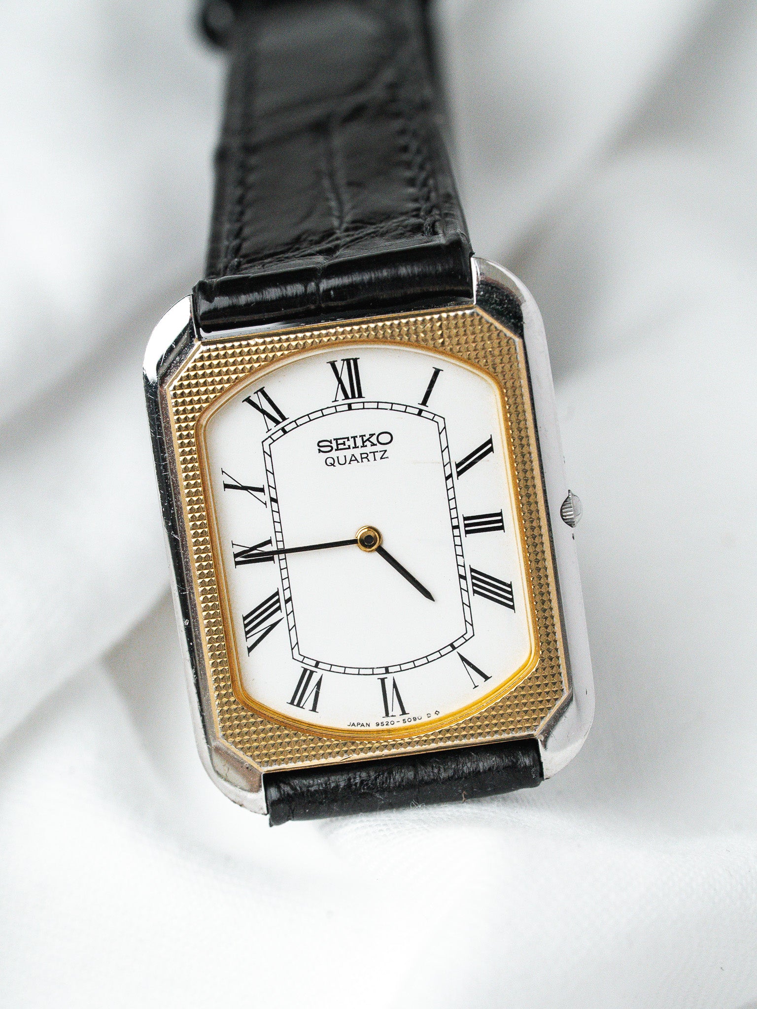 Seiko Quartz vintage watch with gold bezel, white dial, Roman numerals, black leather strap