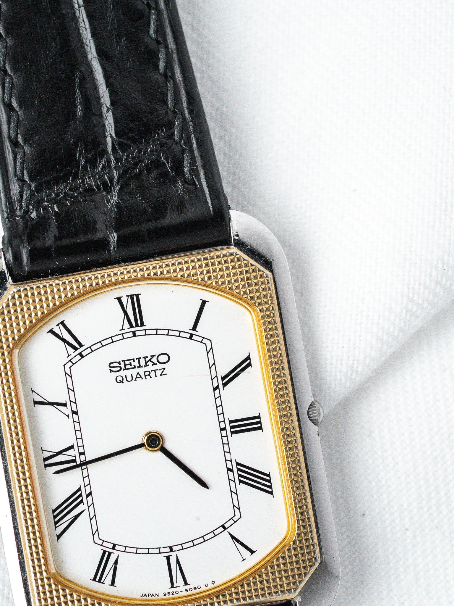 Seiko Quartz vintage watch with gold-tone case, white dial, Roman numerals, black leather strap