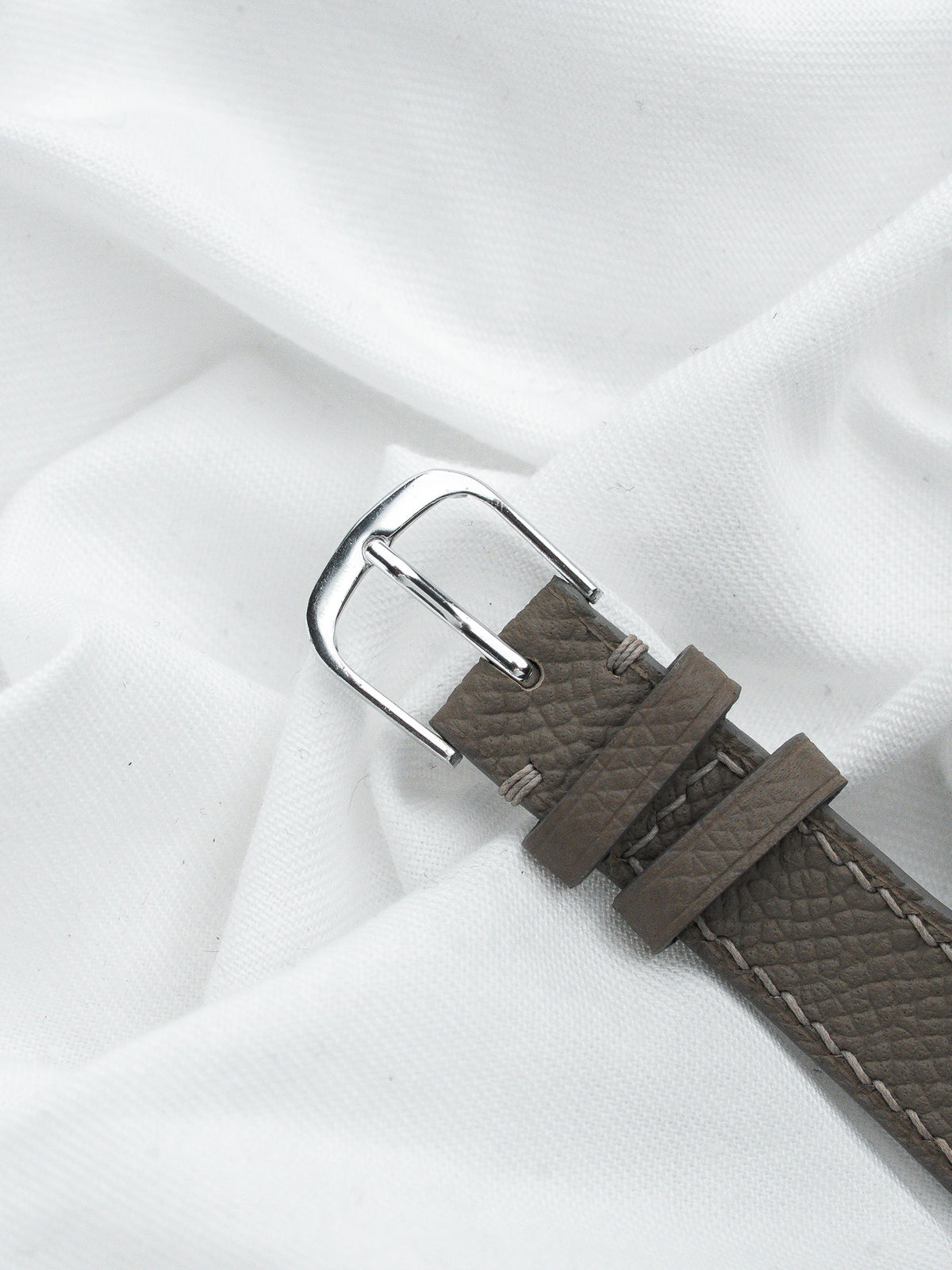 Boucle de bracelet de montre en acier avec bracelet en cuir gris sur fond blanc