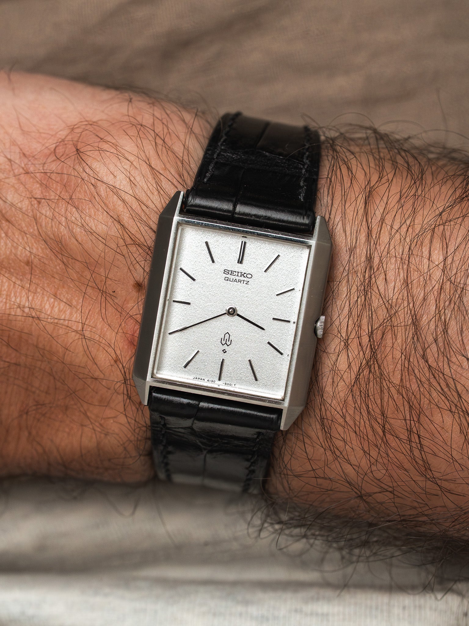 Seiko Quartz vintage watch with silver dial and black leather strap on wrist