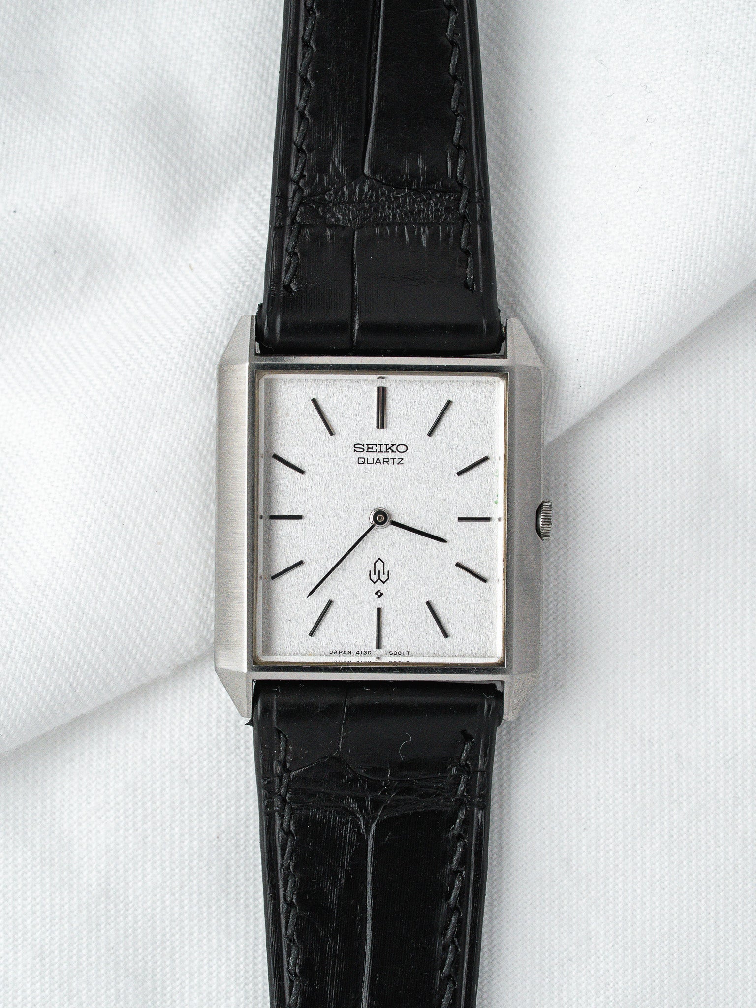 Seiko Quartz vintage watch with silver case, white dial, black leather strap on white fabric