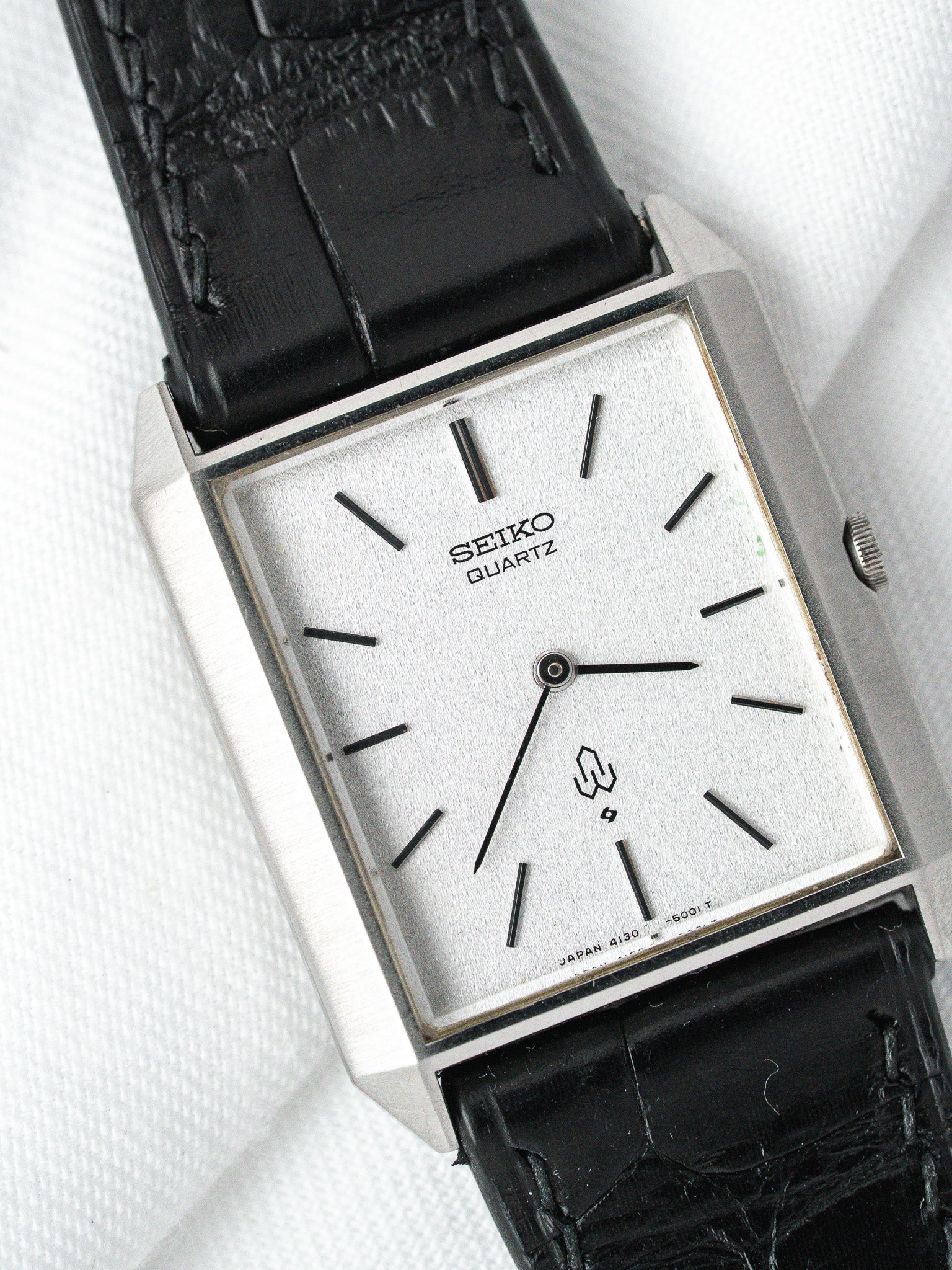 Seiko Quartz vintage watch with silver dial, black markers, and black leather strap