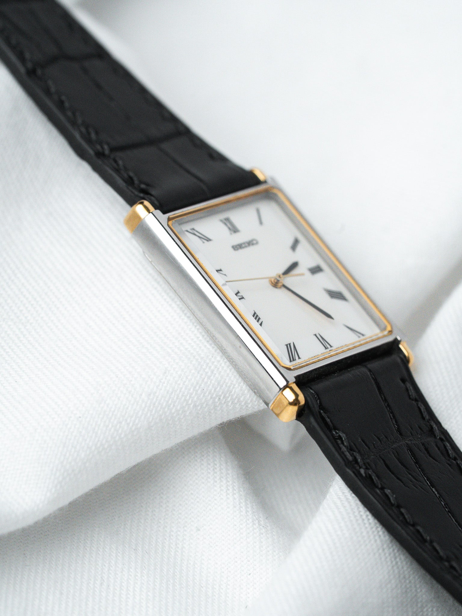 Seiko vintage watch with rectangular case, white dial, Roman numerals, black leather strap