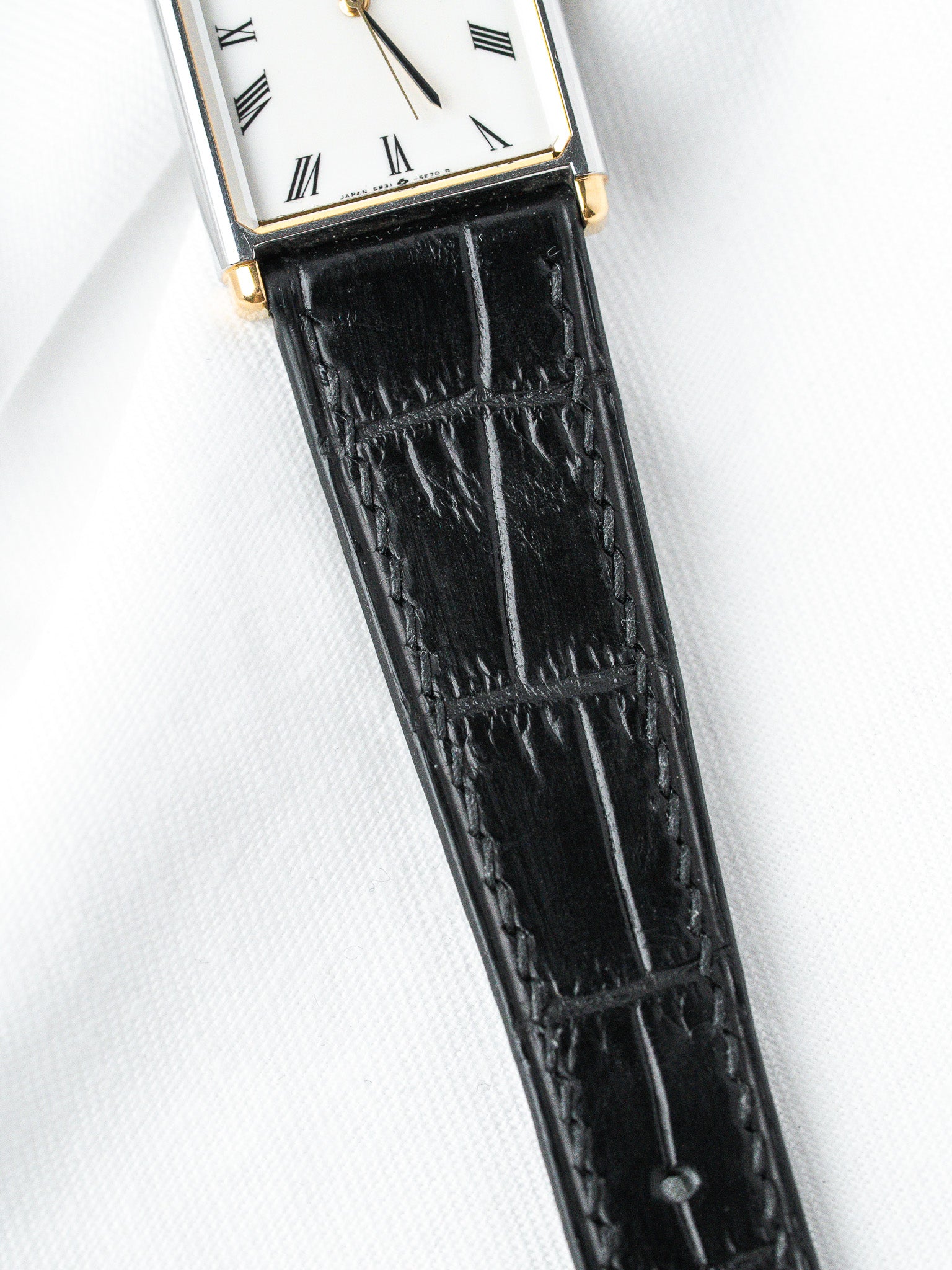 Vintage Seiko rectangular watch with white dial, gold accents, black alligator strap on white background
