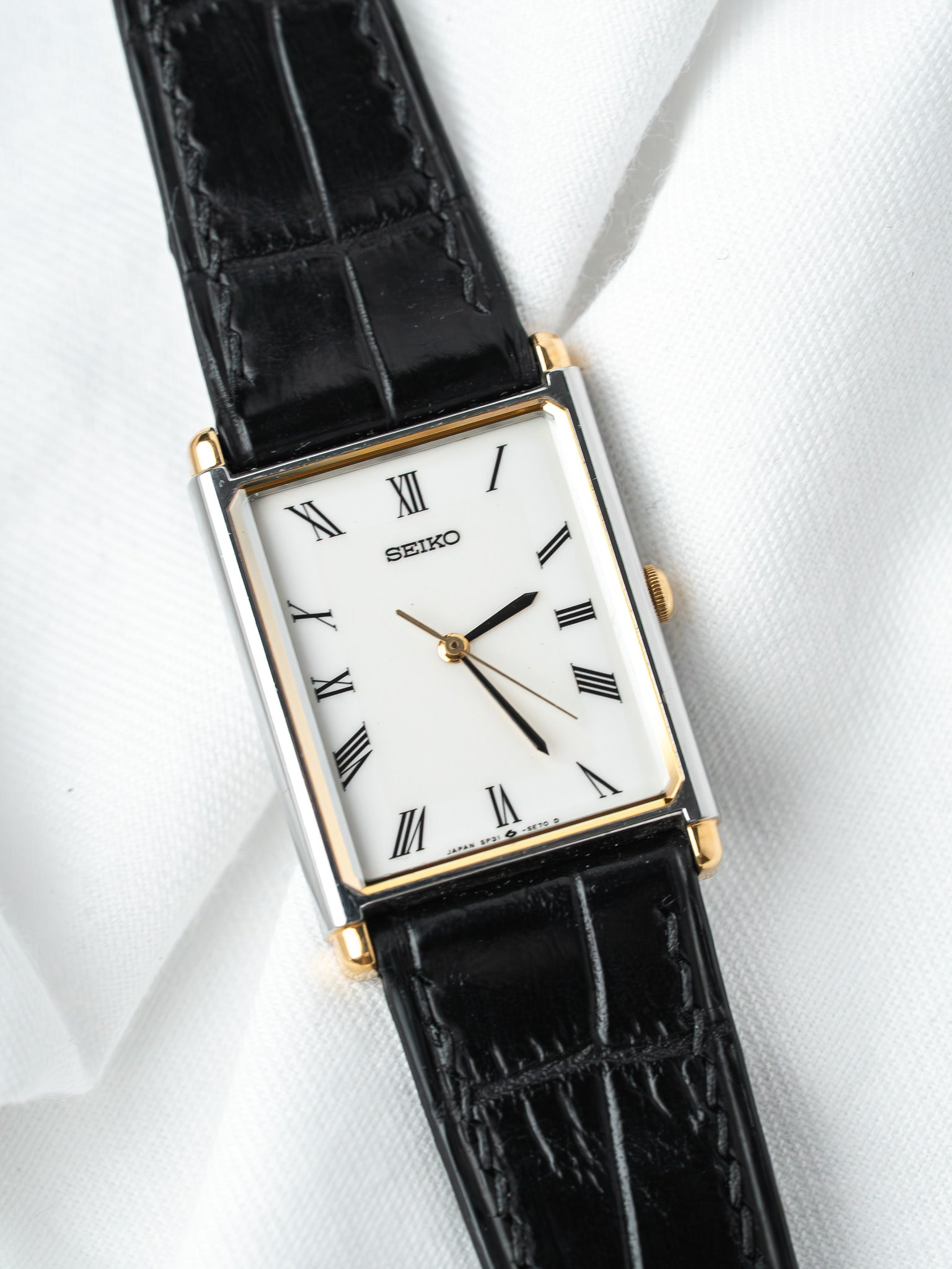 Seiko vintage rectangular watch with white dial, Roman numerals, gold accents, black leather strap