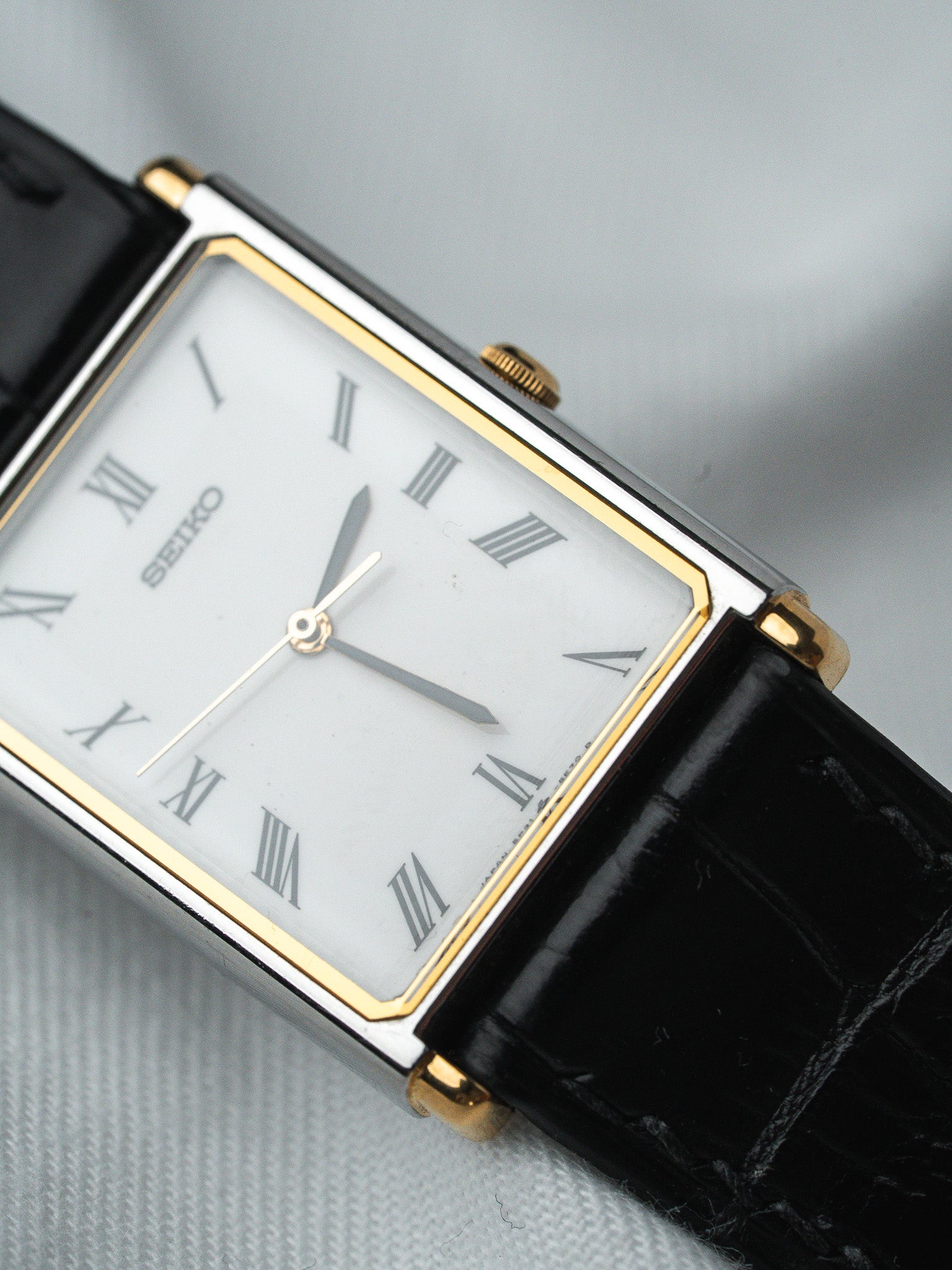 Seiko vintage watch with rectangular case, white dial, Roman numerals, black leather strap