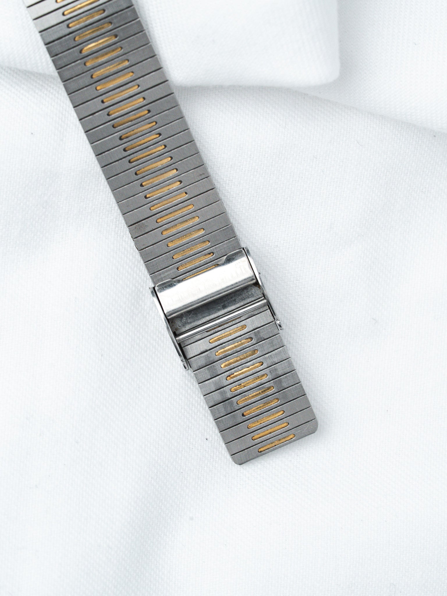 Vintage Omega Seamaster bracelet in steel with gold accents, laid on white fabric