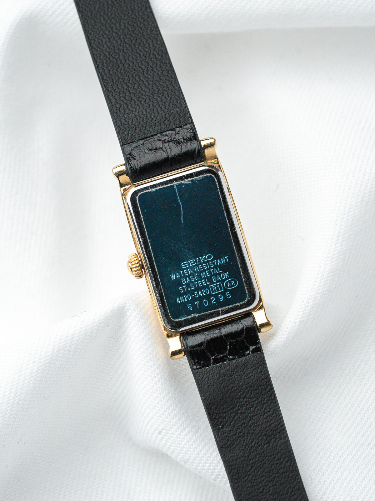 Seiko vintage watch with gold case, black leather strap, and blue case back