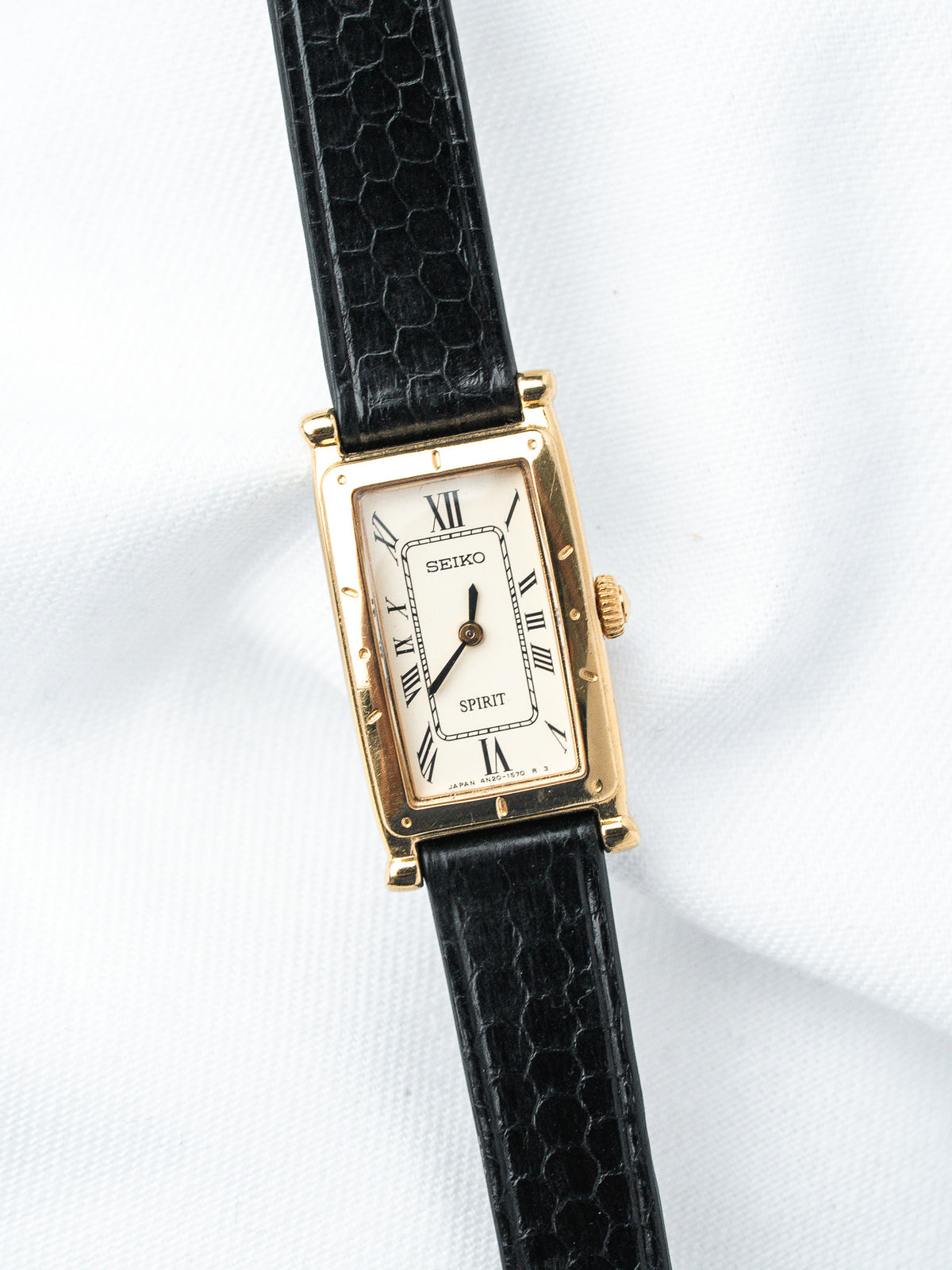 Seiko Spirit vintage watch with gold case, white dial, Roman numerals, black textured strap
