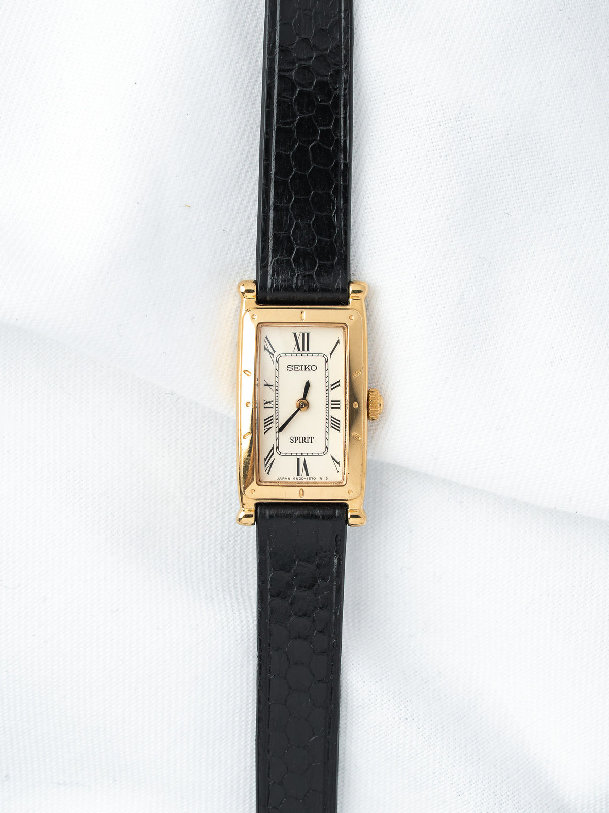Seiko Spirit vintage watch with gold case, white dial, Roman numerals, black textured strap