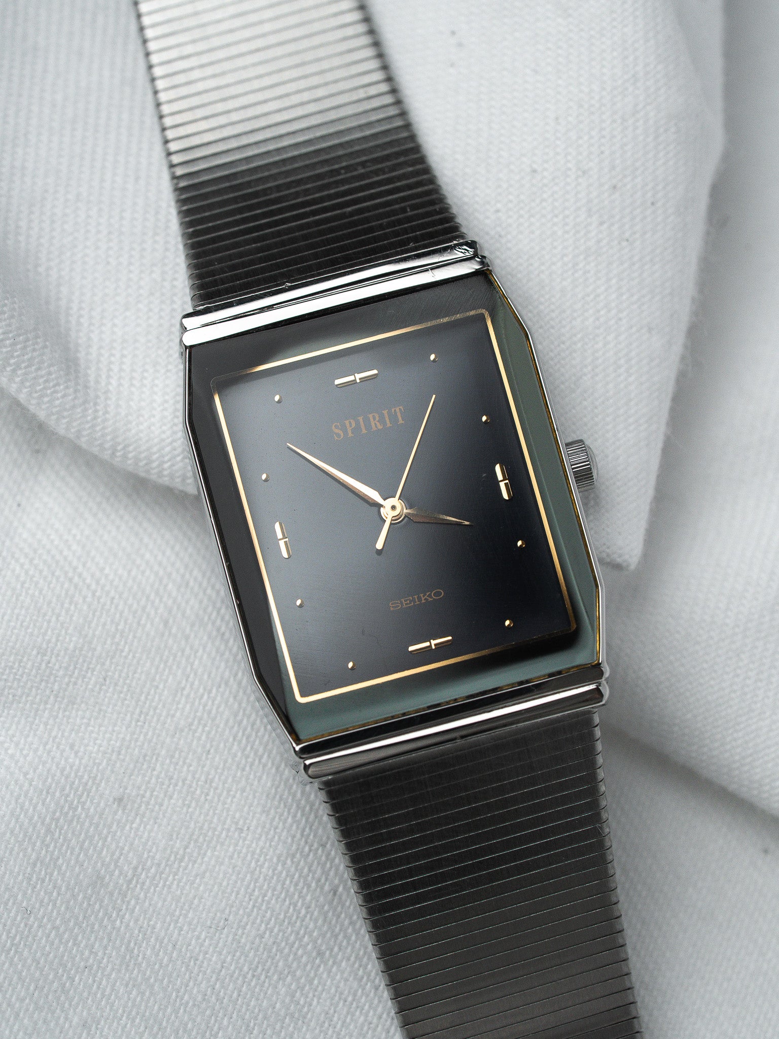Seiko Spirit vintage watch with black dial, gold markers, and ribbed metal bracelet
