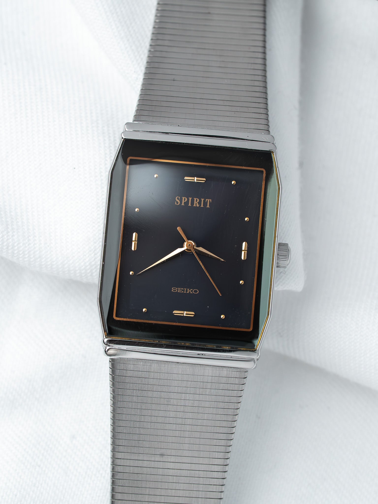 Seiko Spirit vintage watch with black dial, gold markers, and steel mesh bracelet