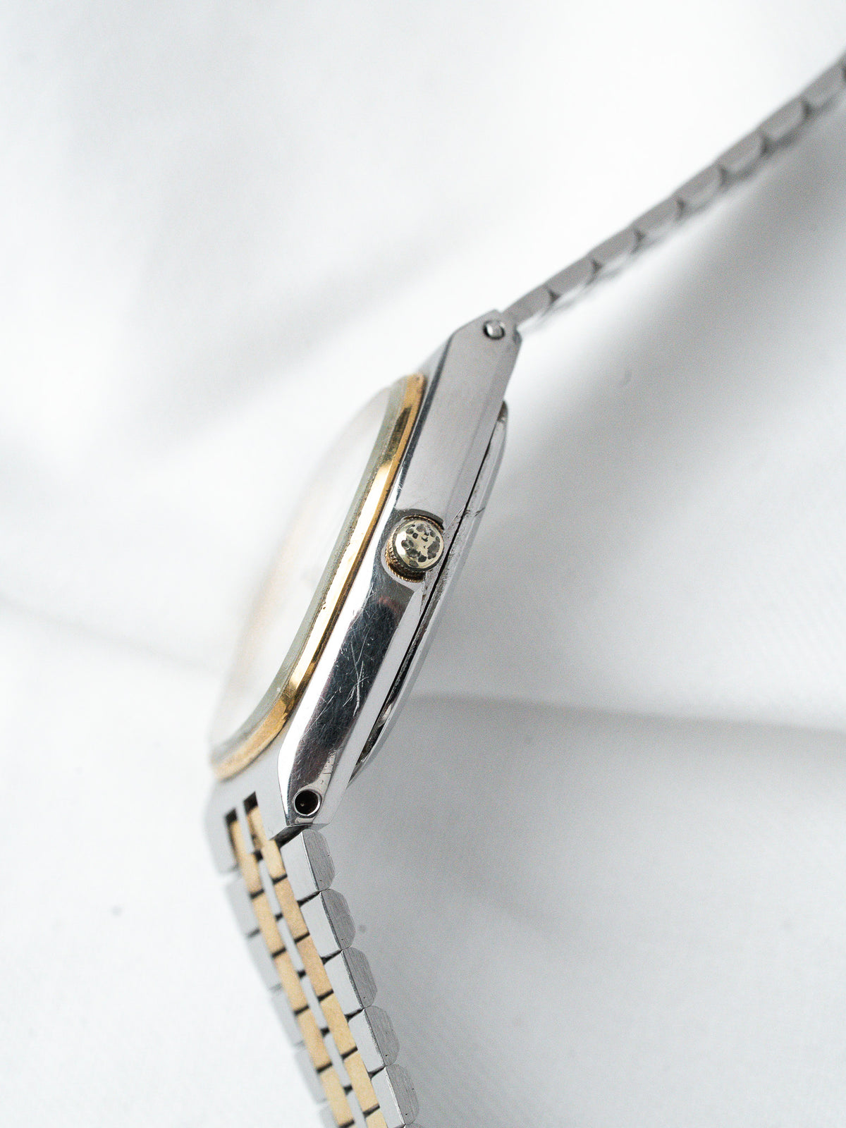 Vintage Omega watch with two-tone steel and gold bracelet, side view on white background