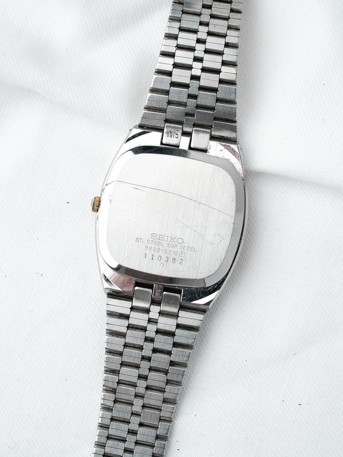 Vintage Seiko watch with stainless steel case and bracelet, back view on white fabric