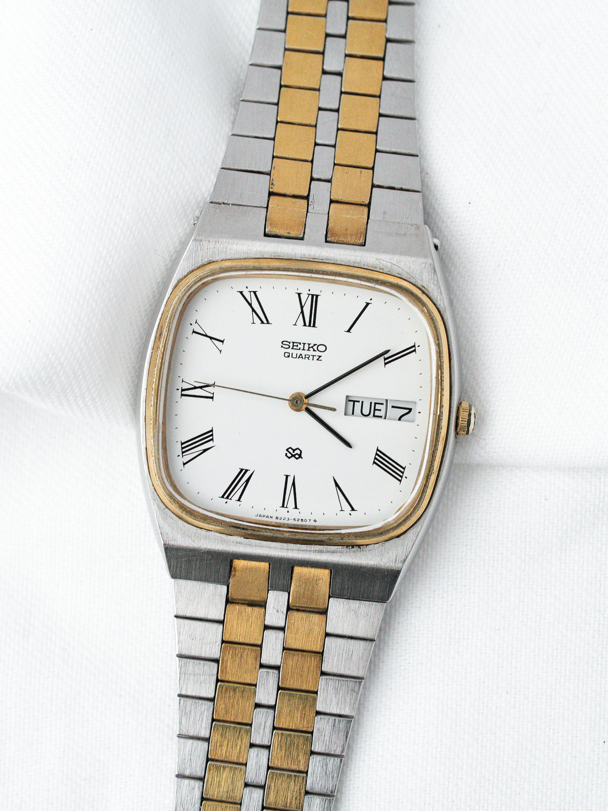 Seiko Quartz vintage watch with white dial, Roman numerals, two-tone bracelet on white background