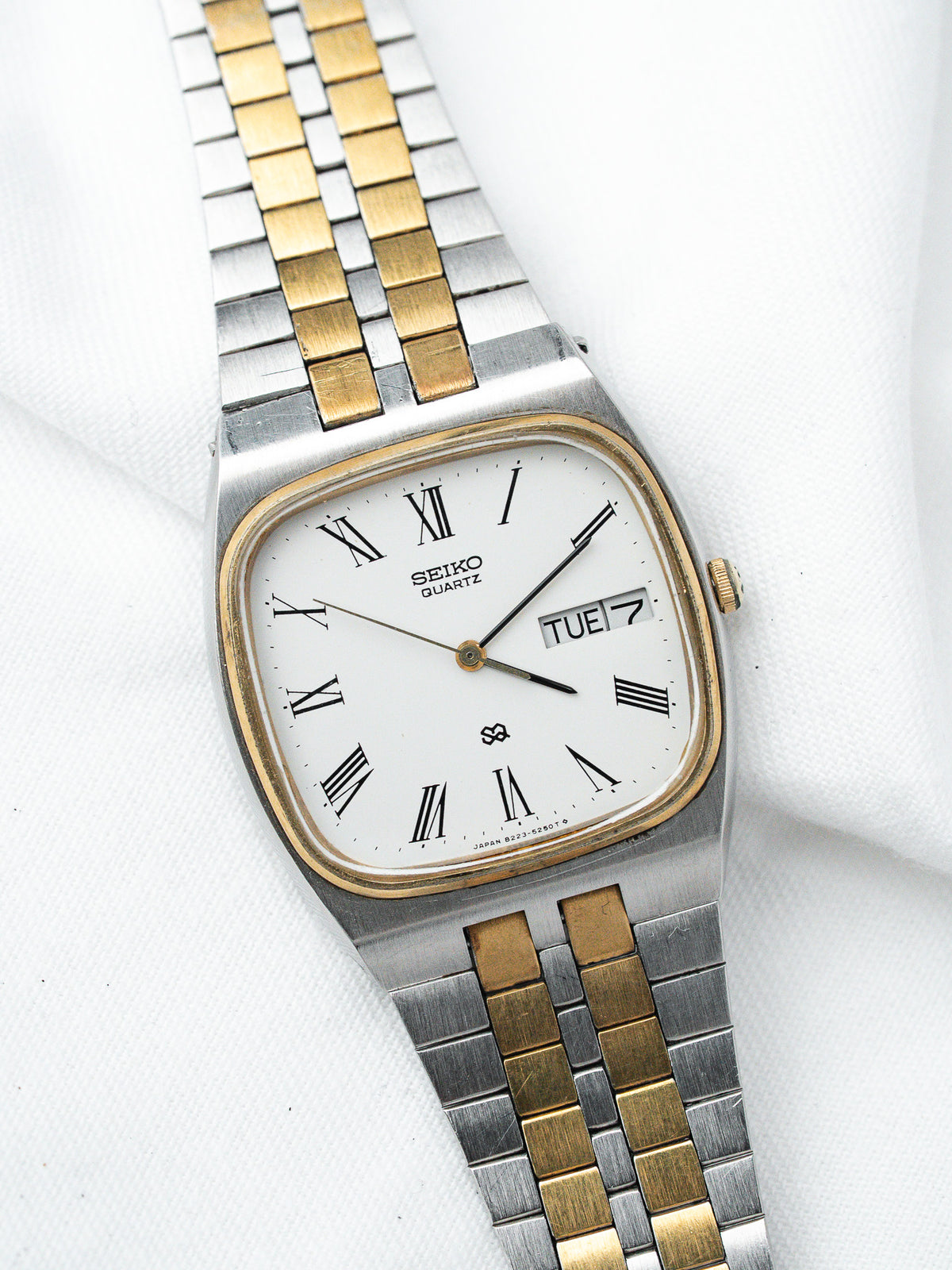 Seiko Quartz vintage watch with white dial, Roman numerals, two-tone bracelet on white background