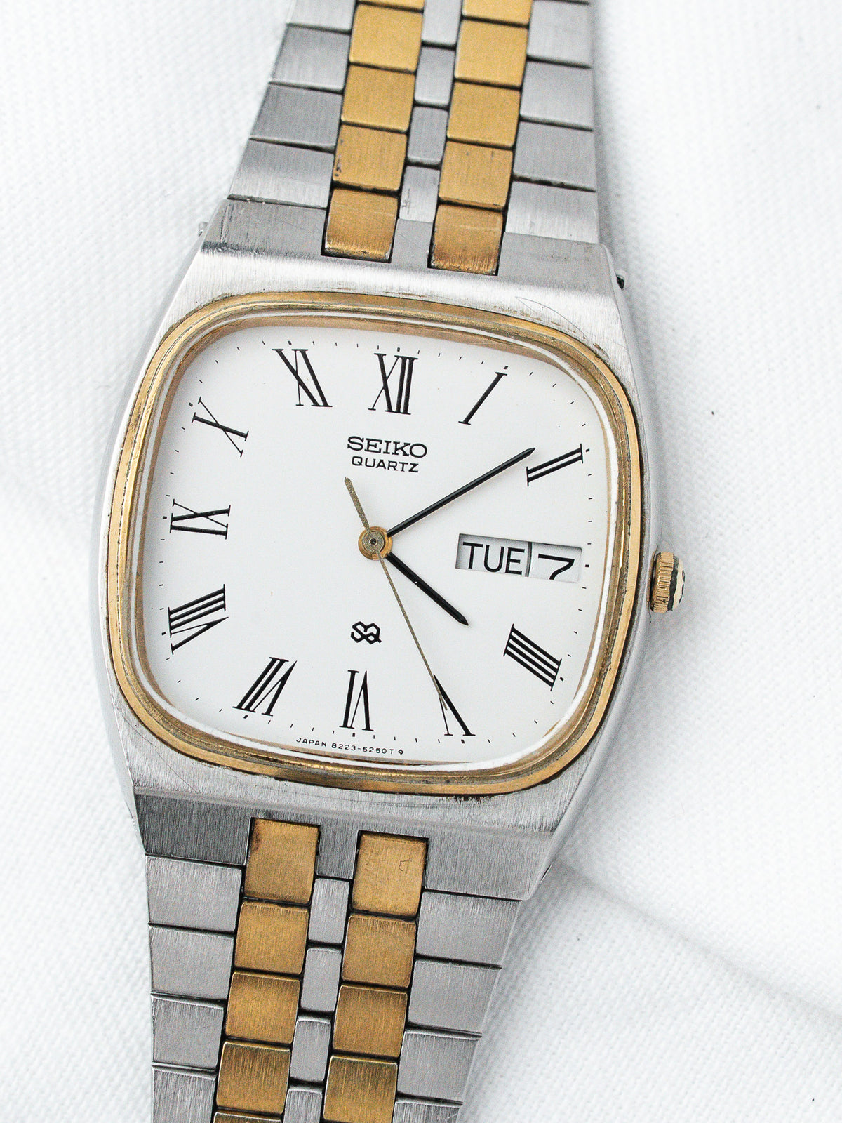 Seiko Quartz vintage watch with white dial, Roman numerals, two-tone bracelet on white background