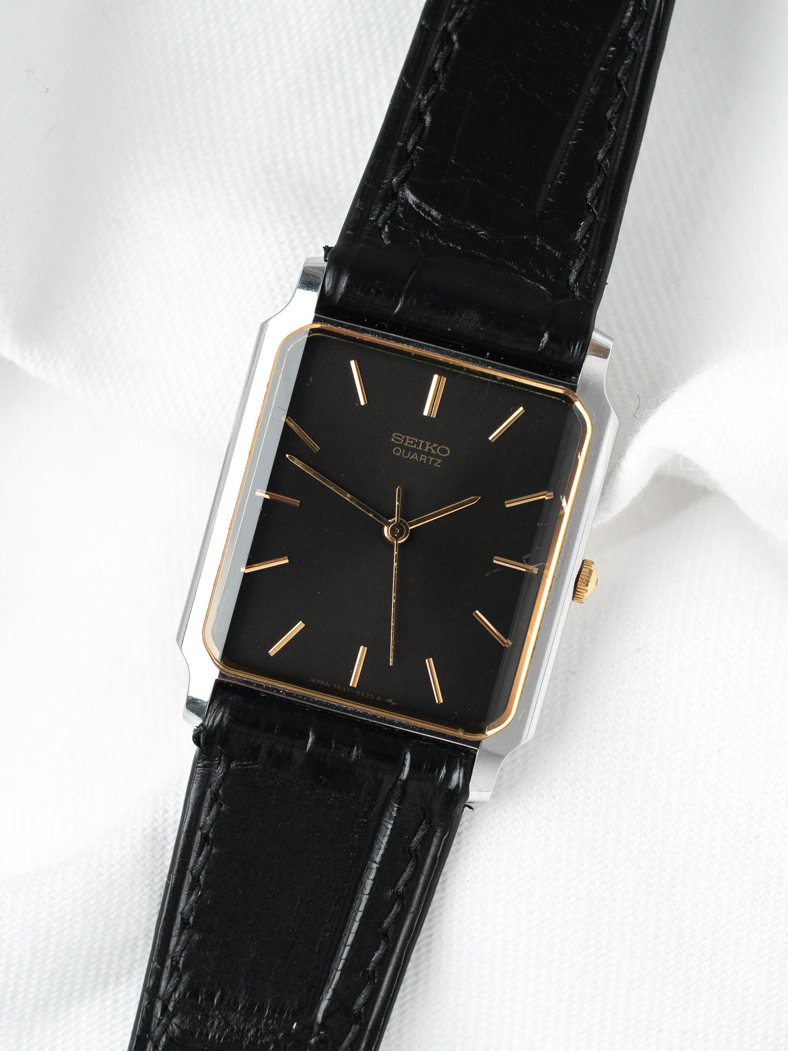 Seiko Quartz vintage watch with black dial, gold markers, and black leather strap