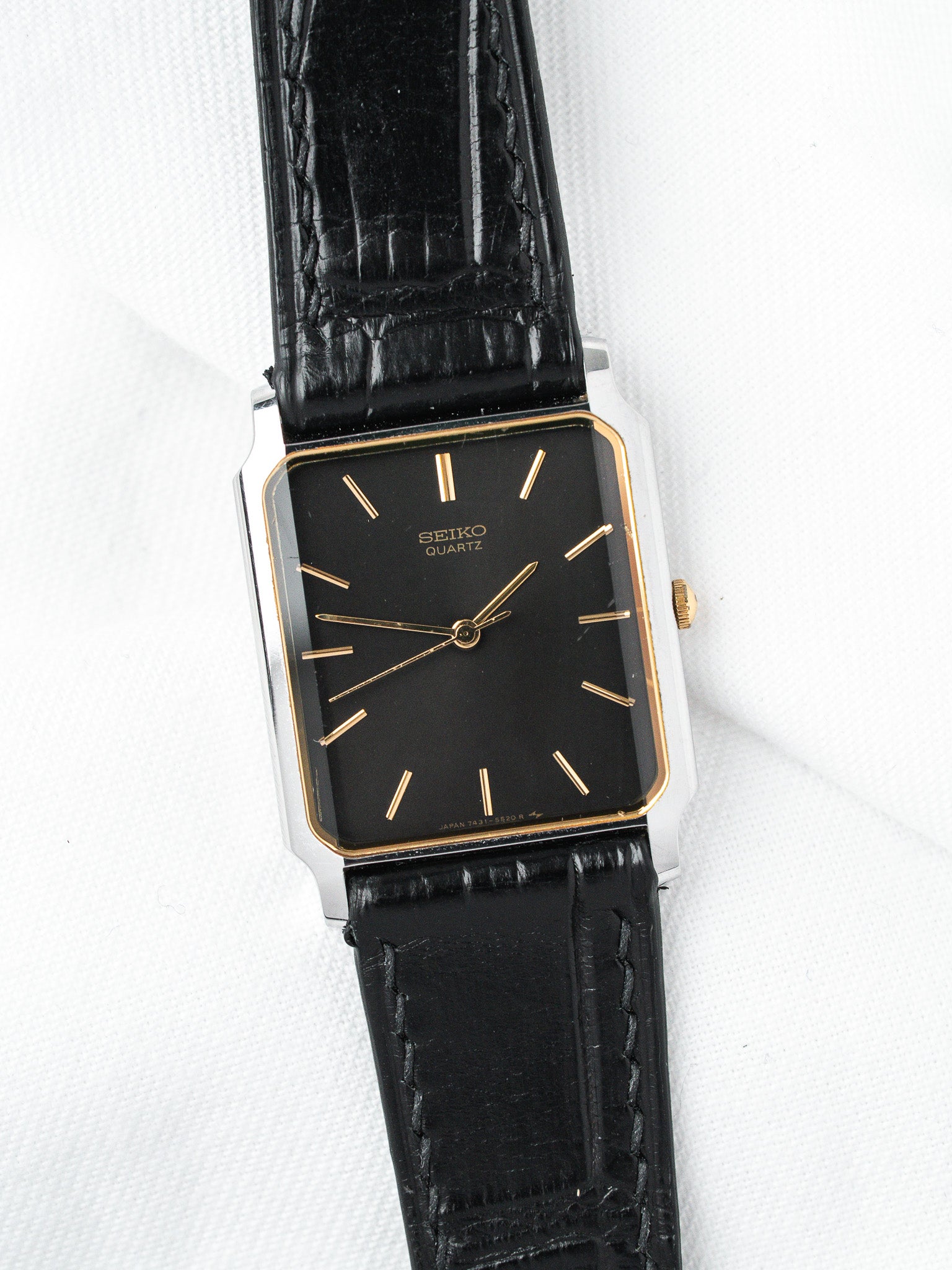 Seiko Quartz vintage watch with black dial, gold markers, and black leather strap