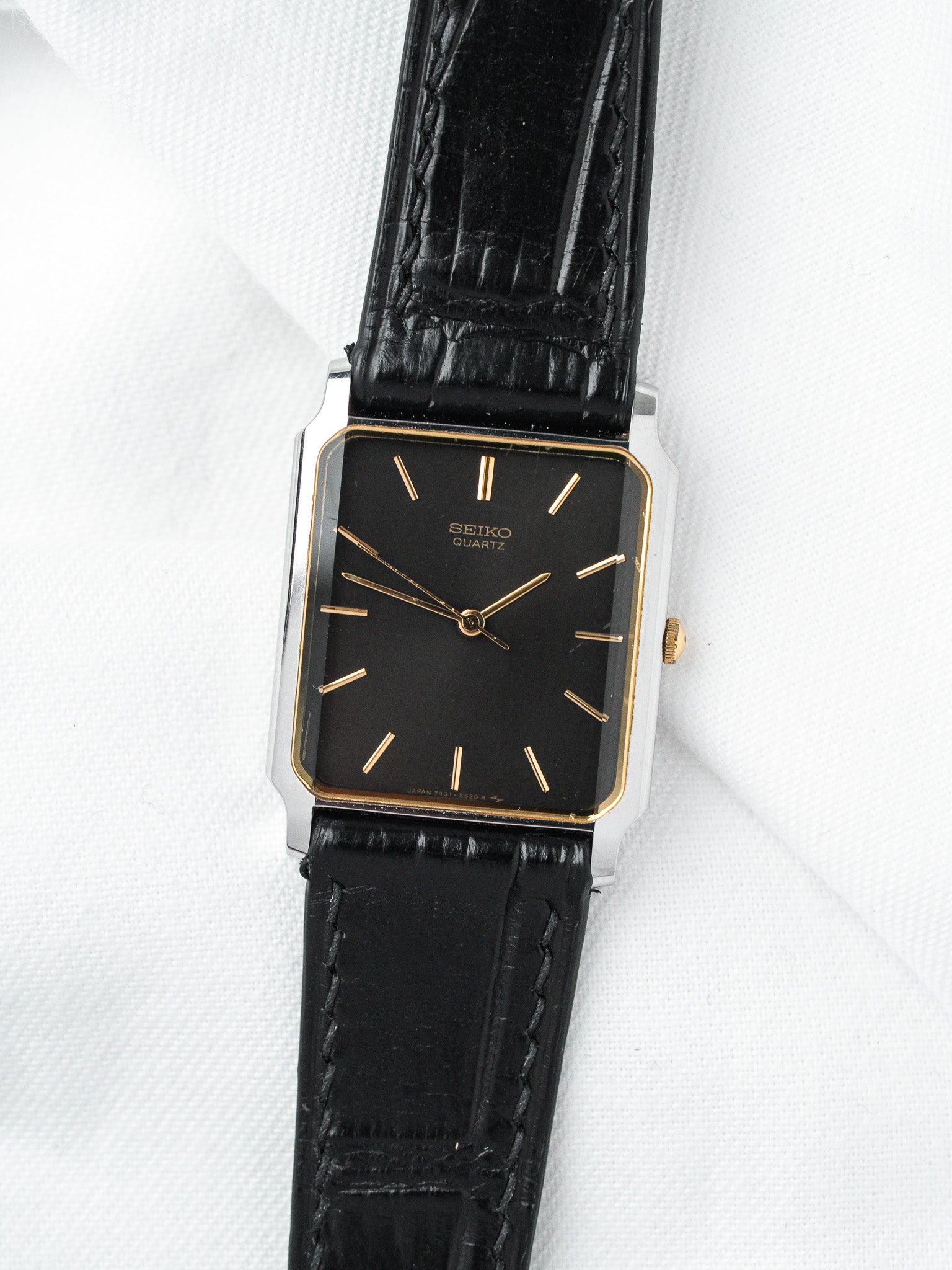 Seiko Quartz vintage watch with black dial, gold markers, and black leather strap