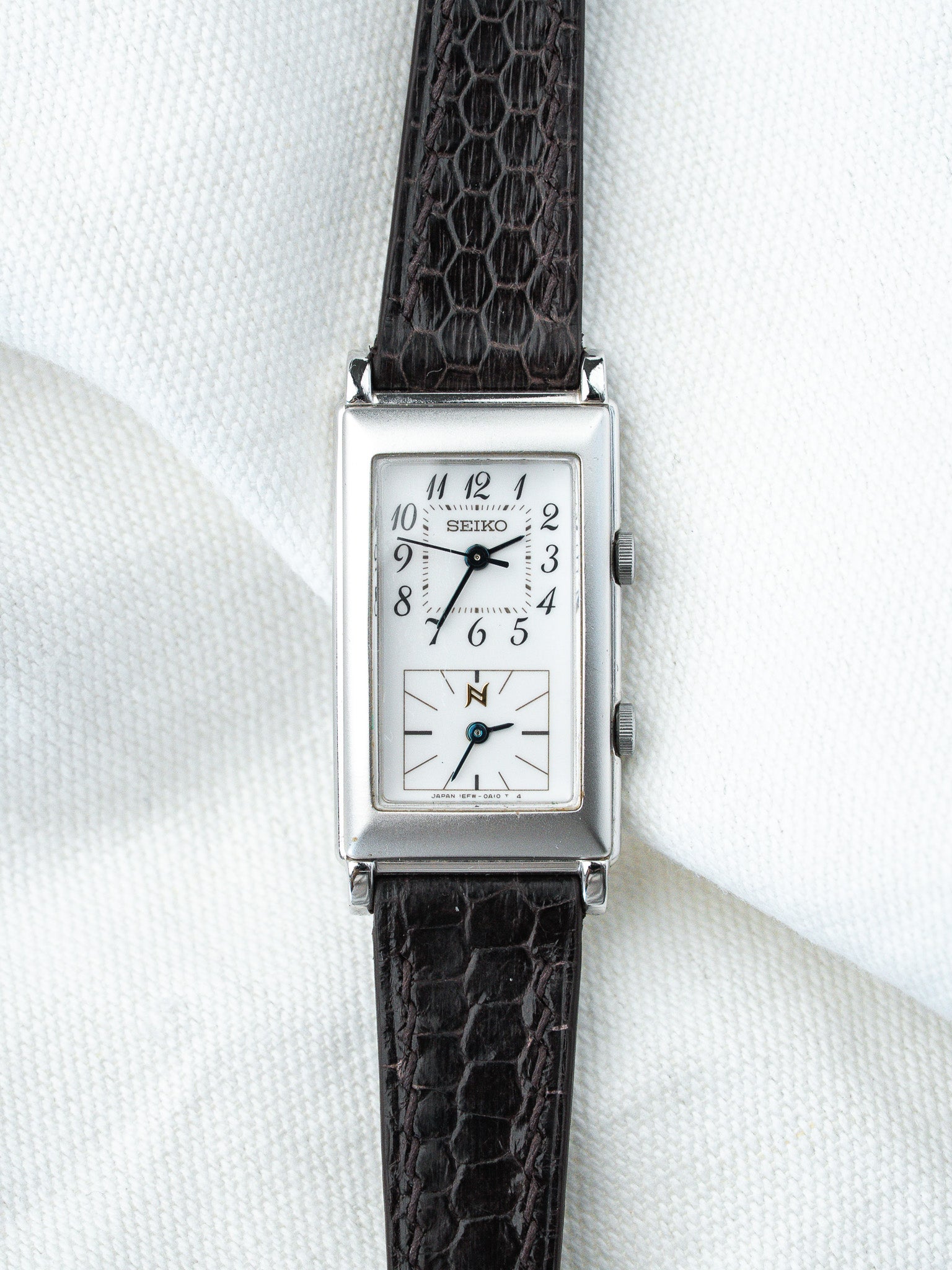Seiko vintage rectangular watch with white dial, black crocodile strap on white fabric