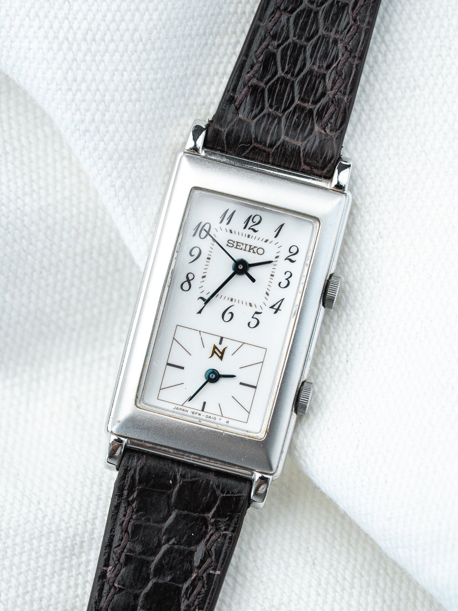 Seiko vintage rectangular watch with white dial, black numerals, and dark textured strap