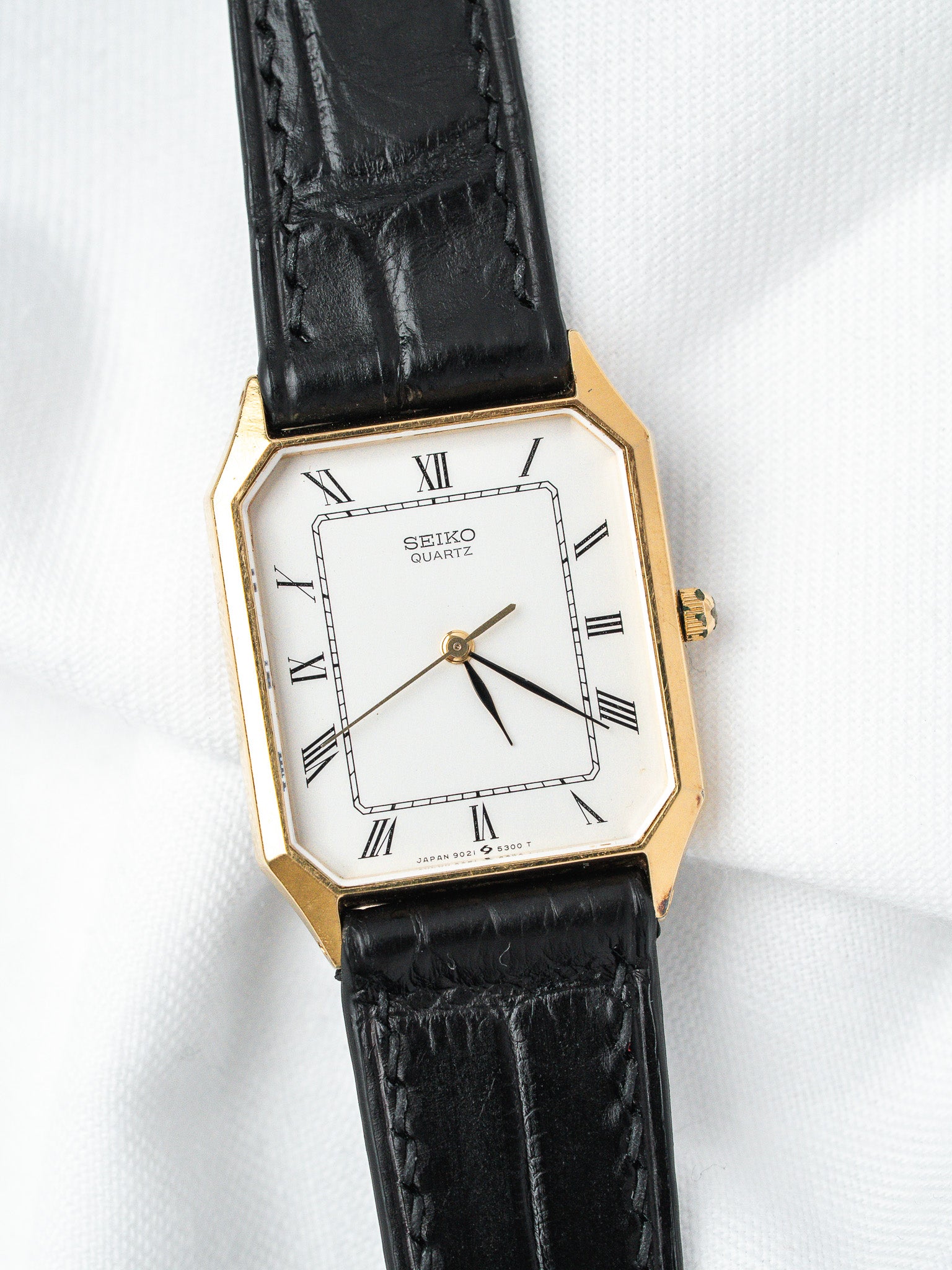 Seiko Quartz vintage watch with gold case, white dial, Roman numerals, black leather strap