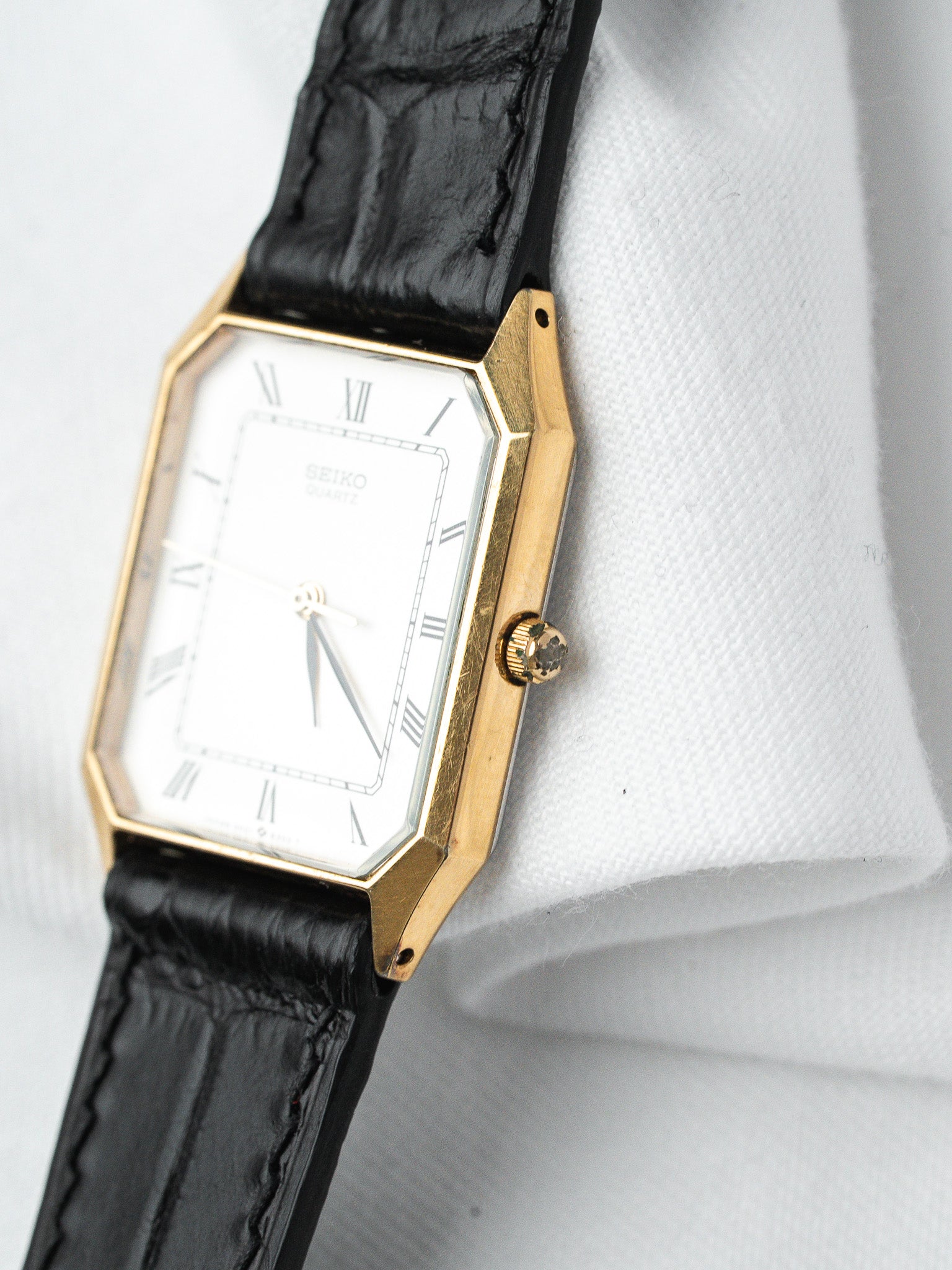 Seiko vintage watch with gold case, white dial, Roman numerals, black leather strap