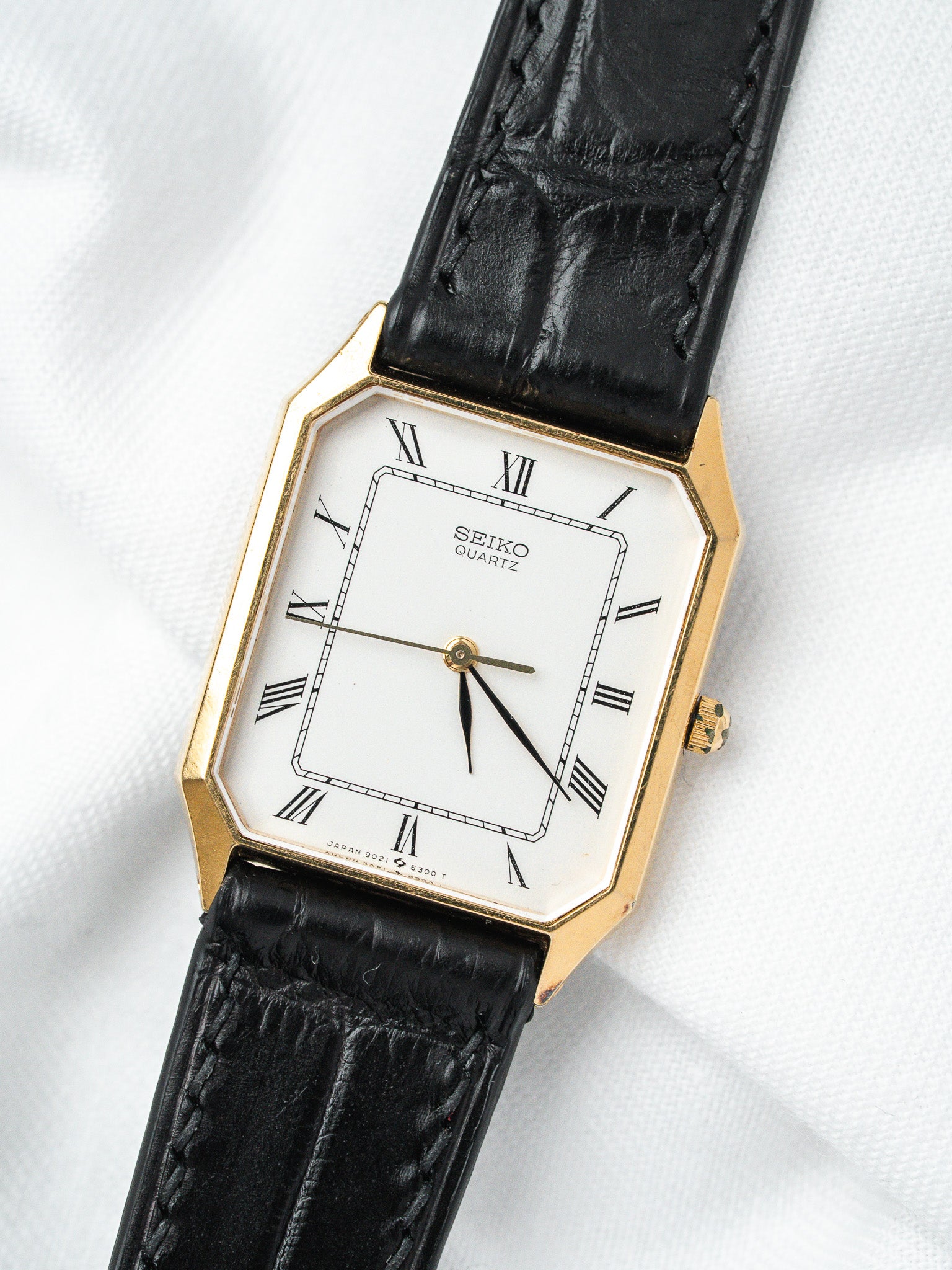 Seiko Quartz vintage watch with gold case, white dial, Roman numerals, black leather strap