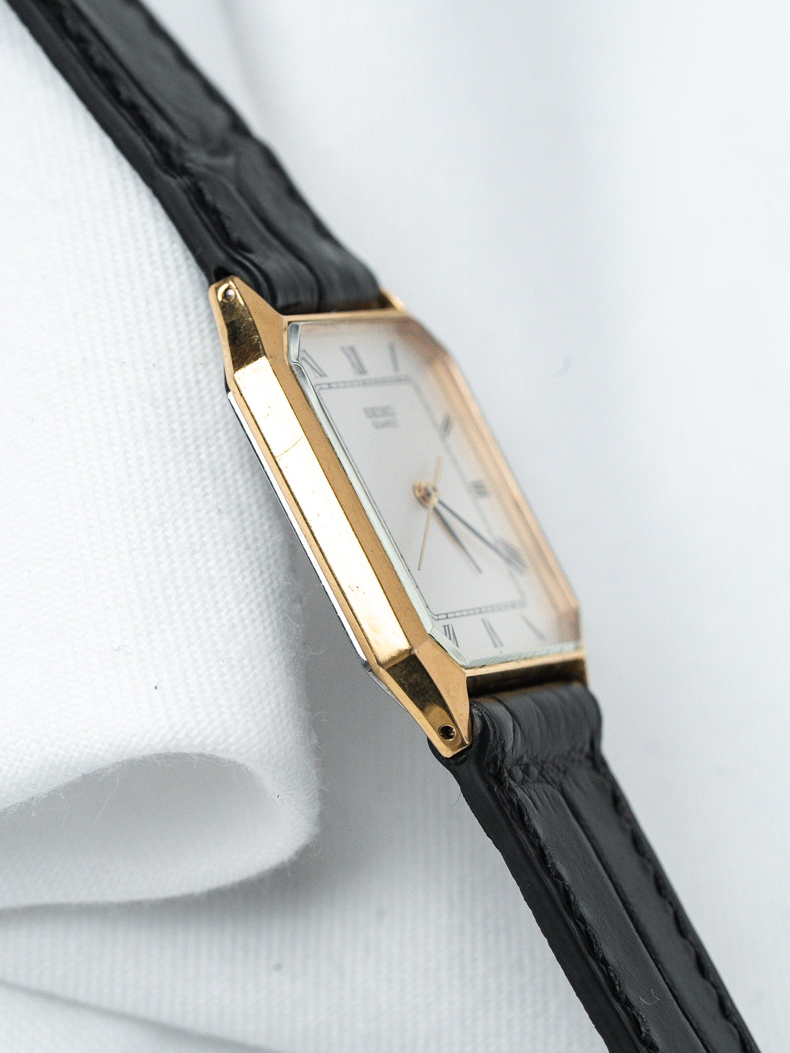 Seiko vintage watch with gold case, white dial, Roman numerals, black leather strap