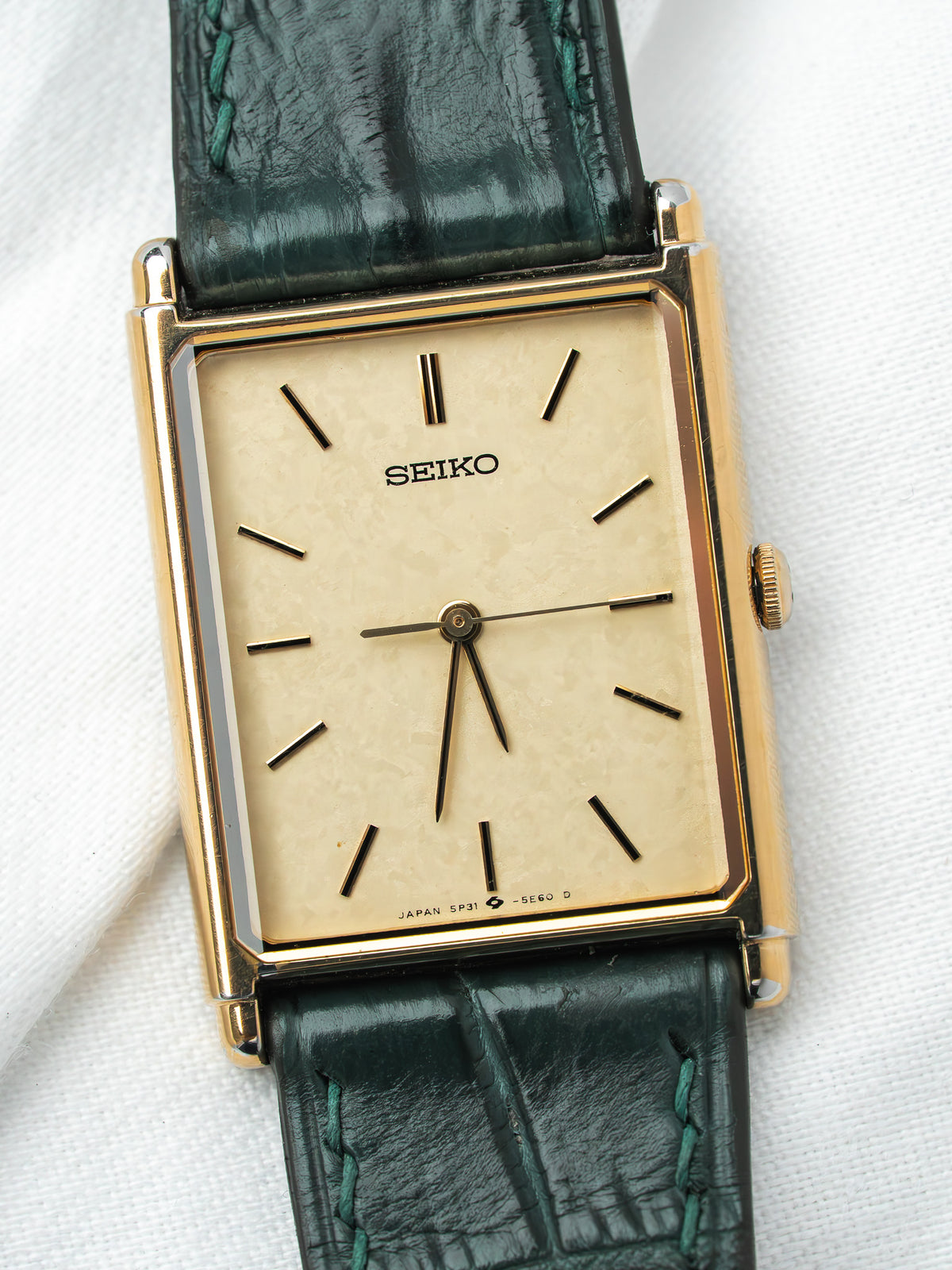 Seiko vintage watch with gold case, cream dial, and green leather strap