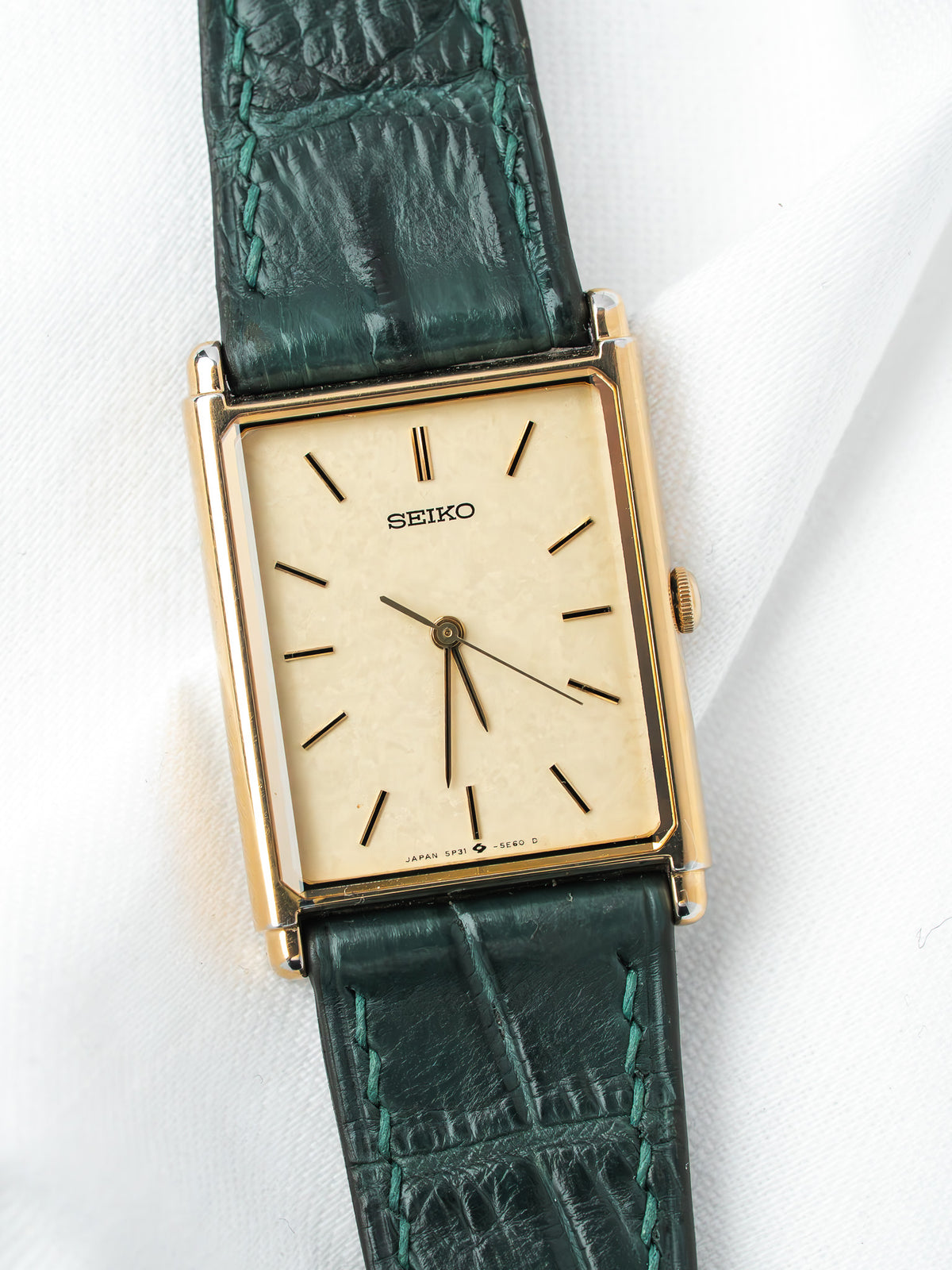 Seiko vintage watch with gold case, cream dial, and green alligator strap