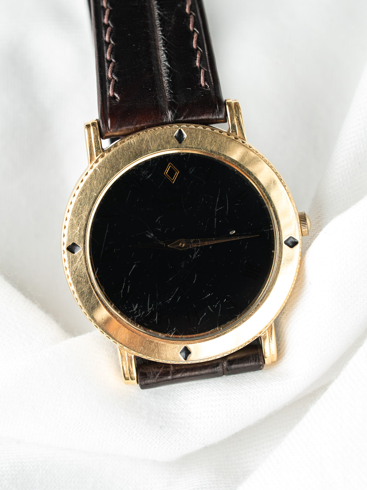 Montre vintage en or, cadran noir minimaliste et bracelet en cuir marron