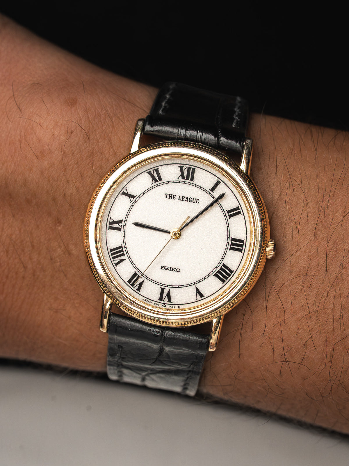 Montre Seiko vintage avec cadran blanc, chiffres romains et bracelet en cuir noir.