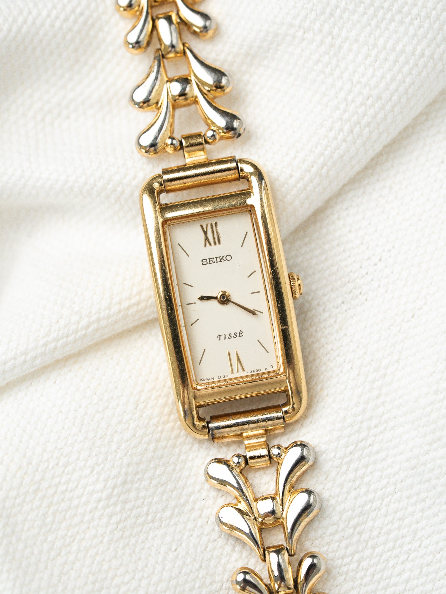Seiko Tissé vintage watch with gold case, white dial, and two-tone floral bracelet