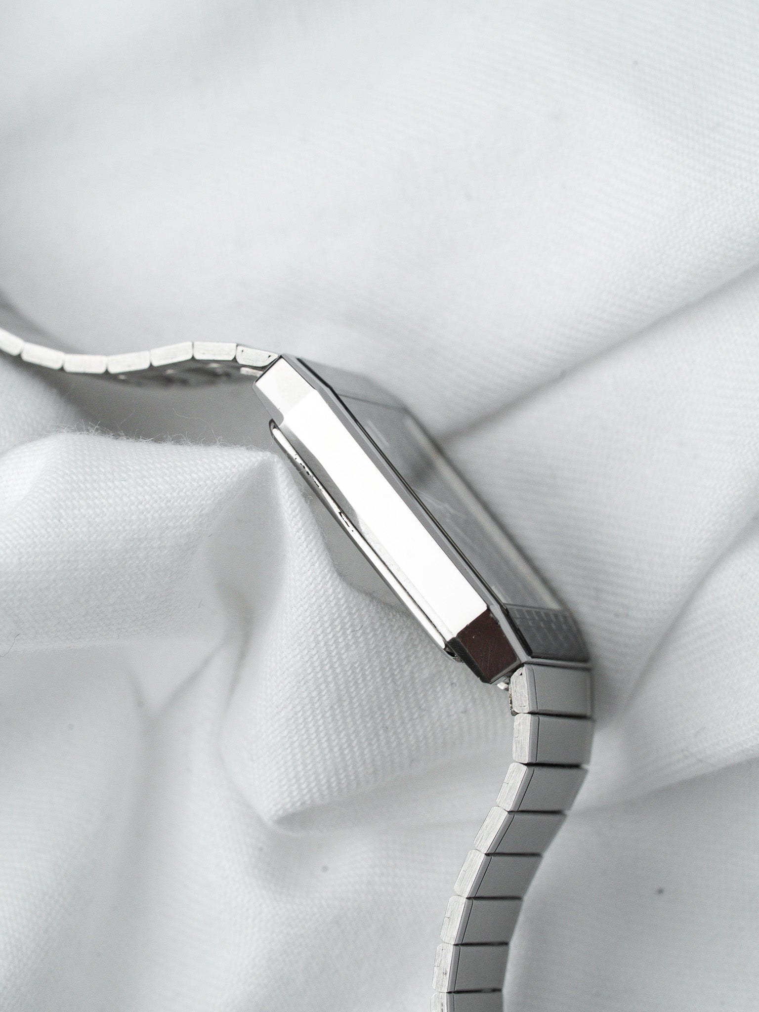 Vintage Cartier watch with rectangular case and metal bracelet on white fabric