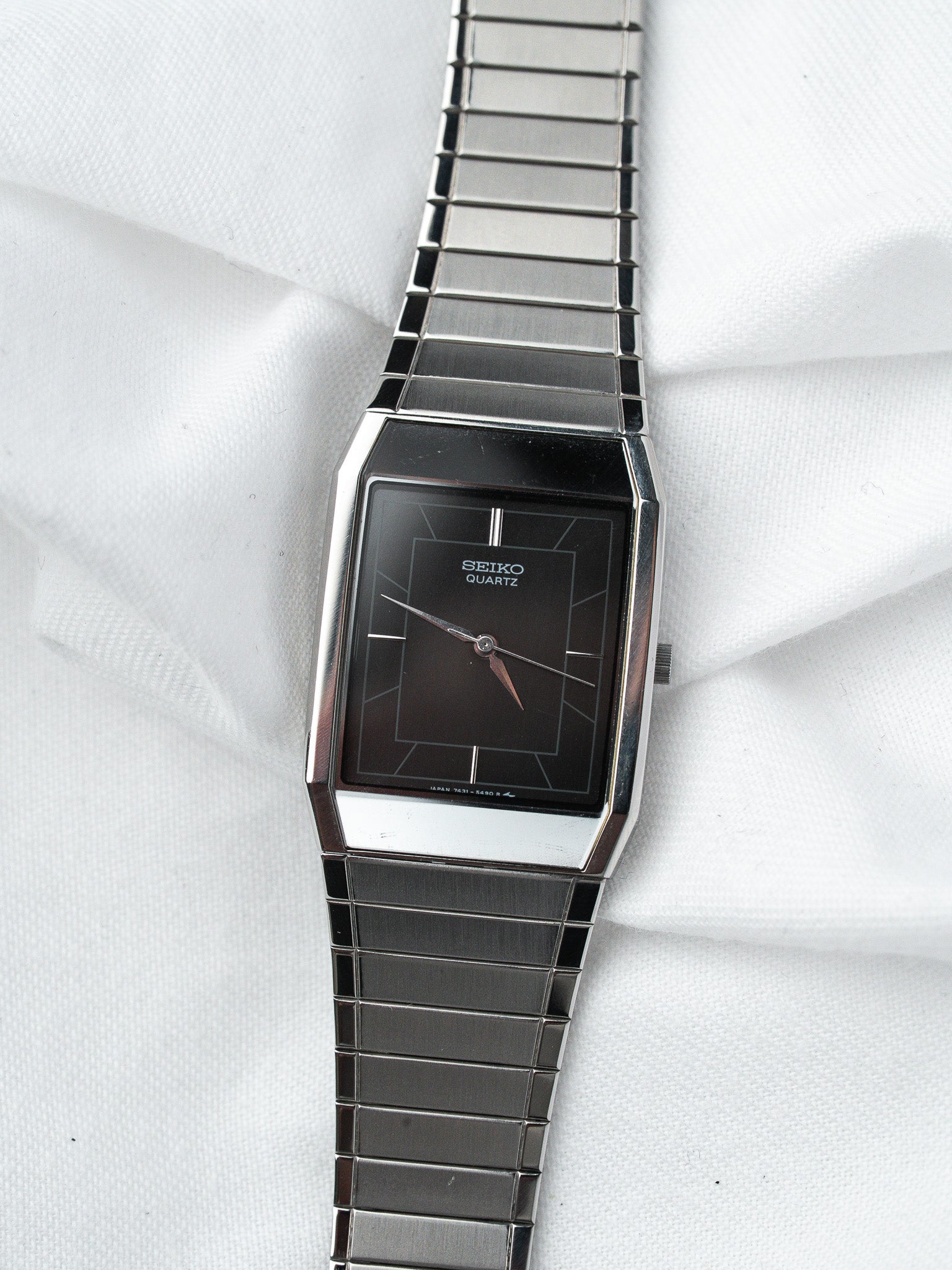Seiko Quartz vintage watch with black dial and stainless steel bracelet on white fabric