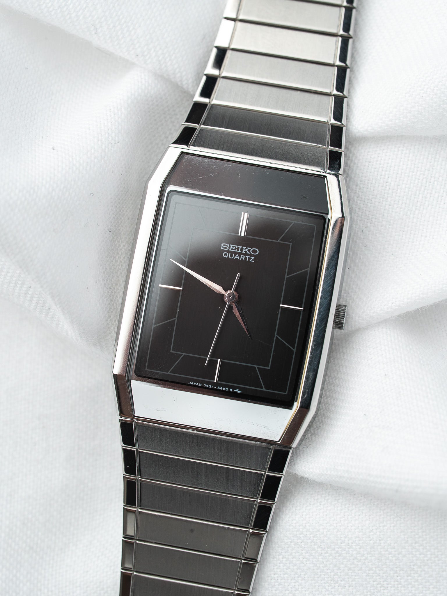 Seiko Quartz vintage watch with black dial and stainless steel bracelet on white fabric
