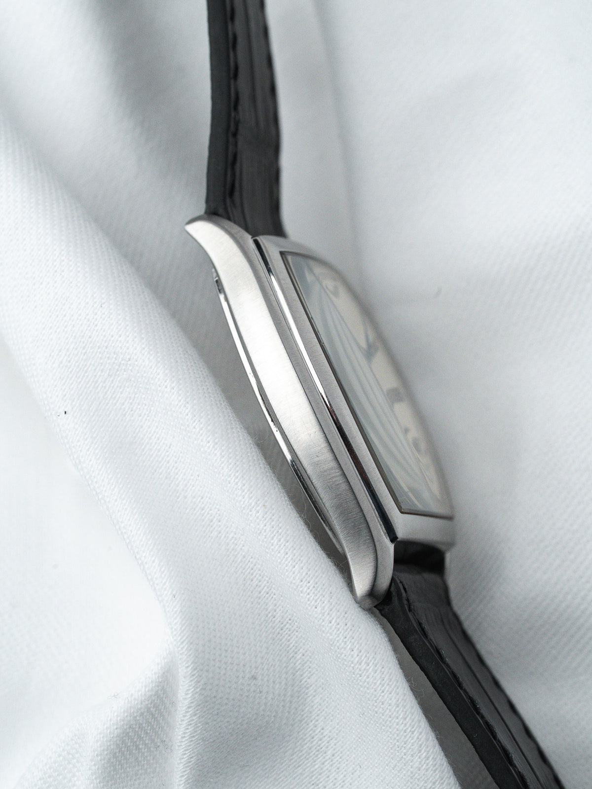 Cartier Tank vintage watch with steel case and black leather strap on white fabric